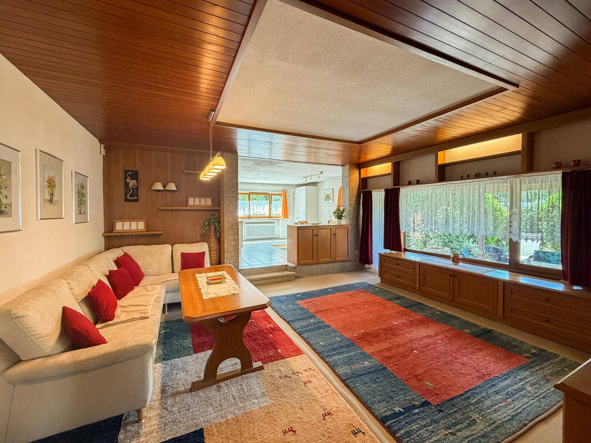 Großzügiges Wohnzimmer mit Holztäfelung an Decke und Wänden, sowie einem gemütlichen Sofa.