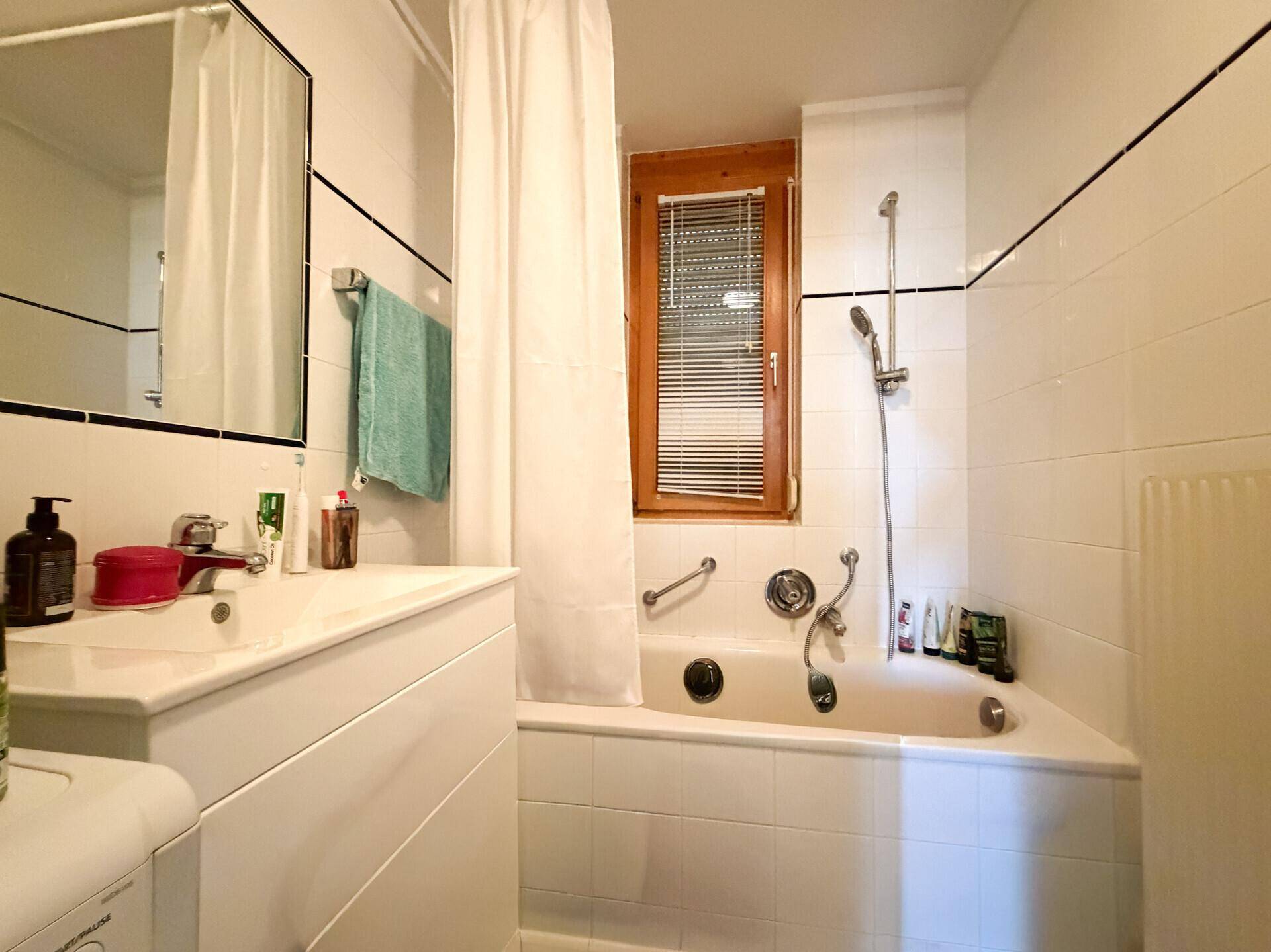Badezimmer mit Badewanne, Waschbecken und Fenster für natürliches Tageslicht.