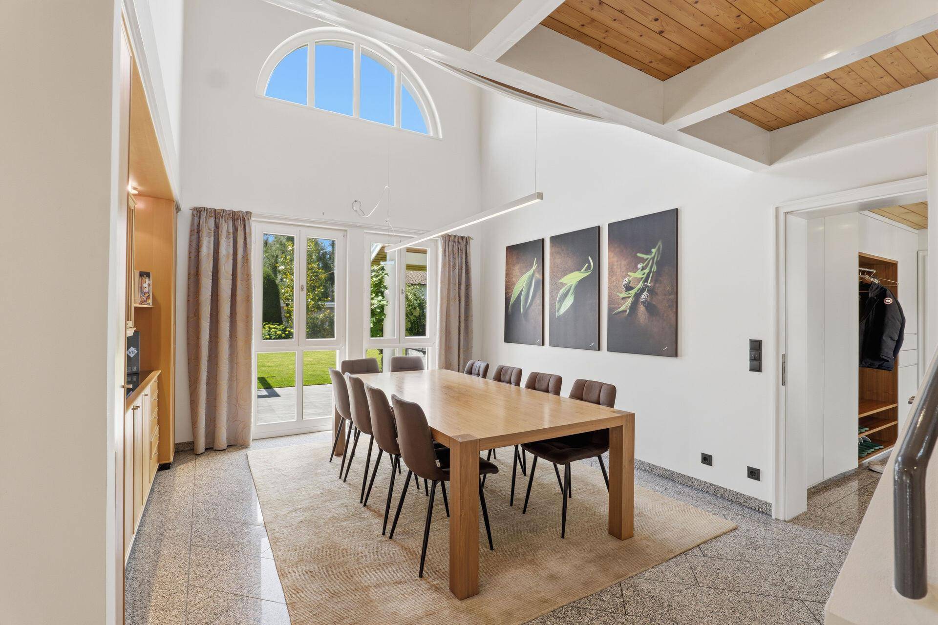 Eleganter Essbereich mit hohen Decken, großem Esstisch und Zugang zum Garten.