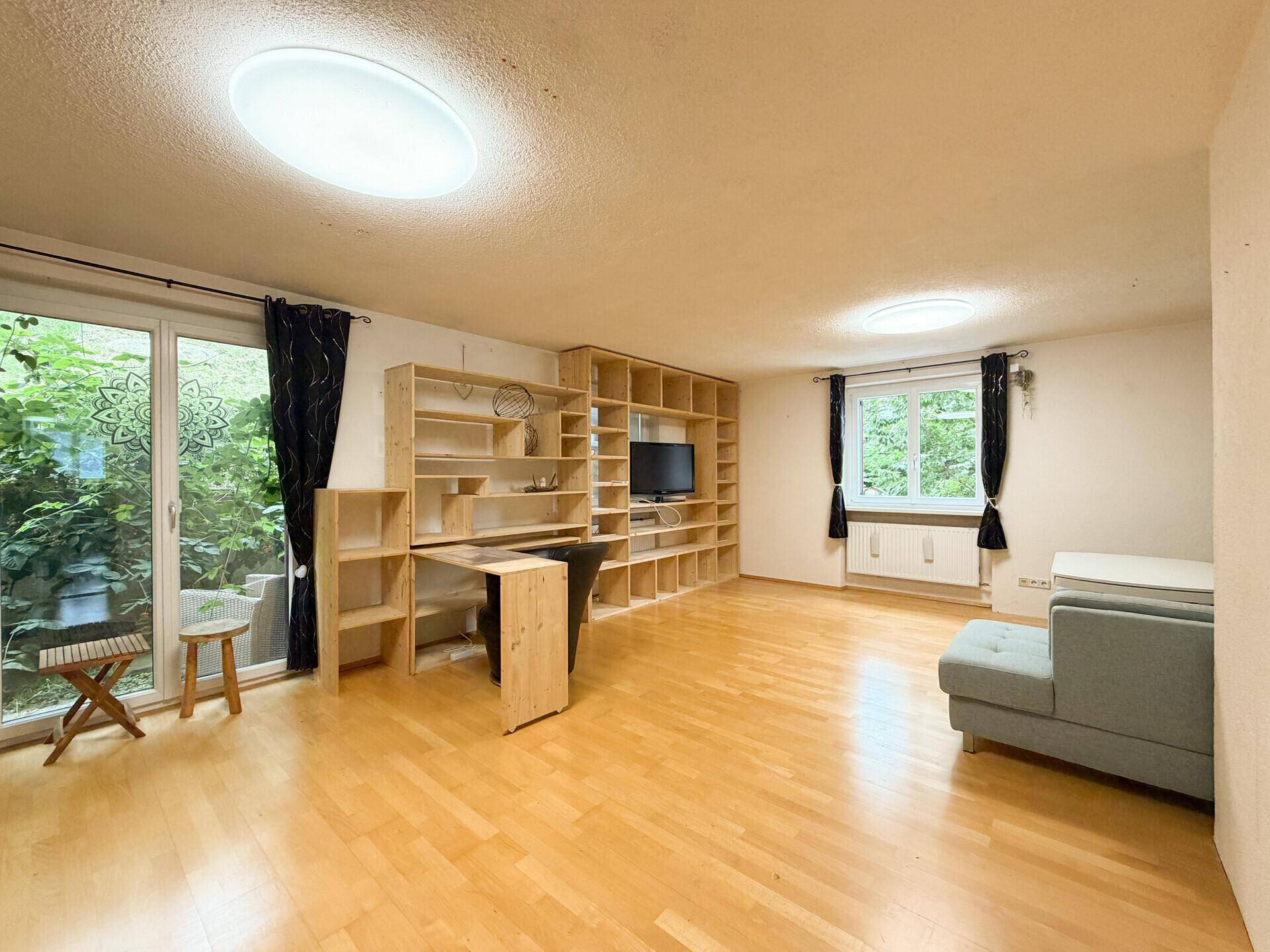 Helles Wohnzimmer mit Zugang zu einem Außenbereich und umfangreichen Holzregalsystemen.