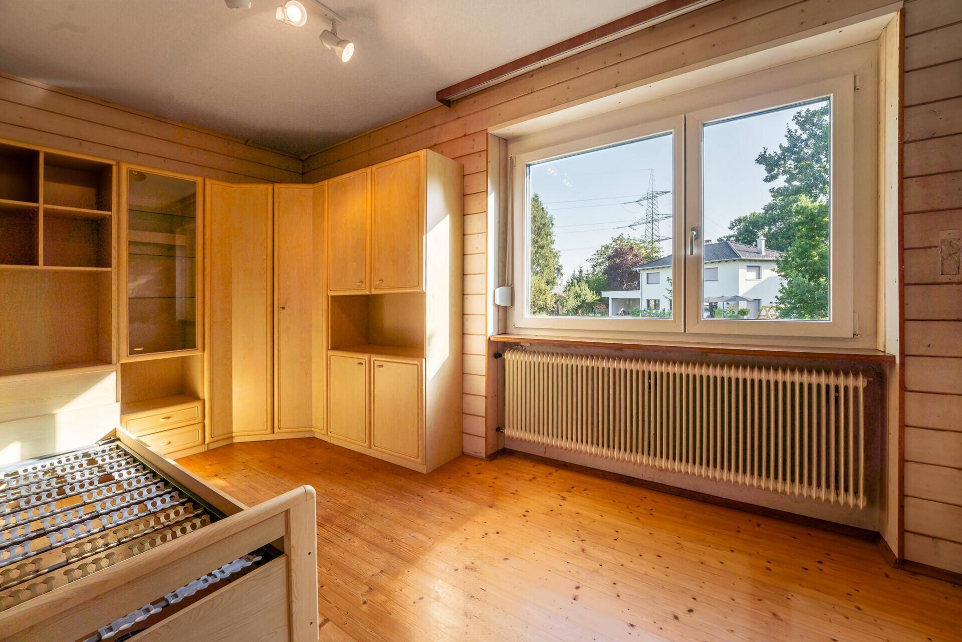 Schlafzimmer mit Holzvertäfelung, Einbauschränken und großem Fenster mit Ausblick.