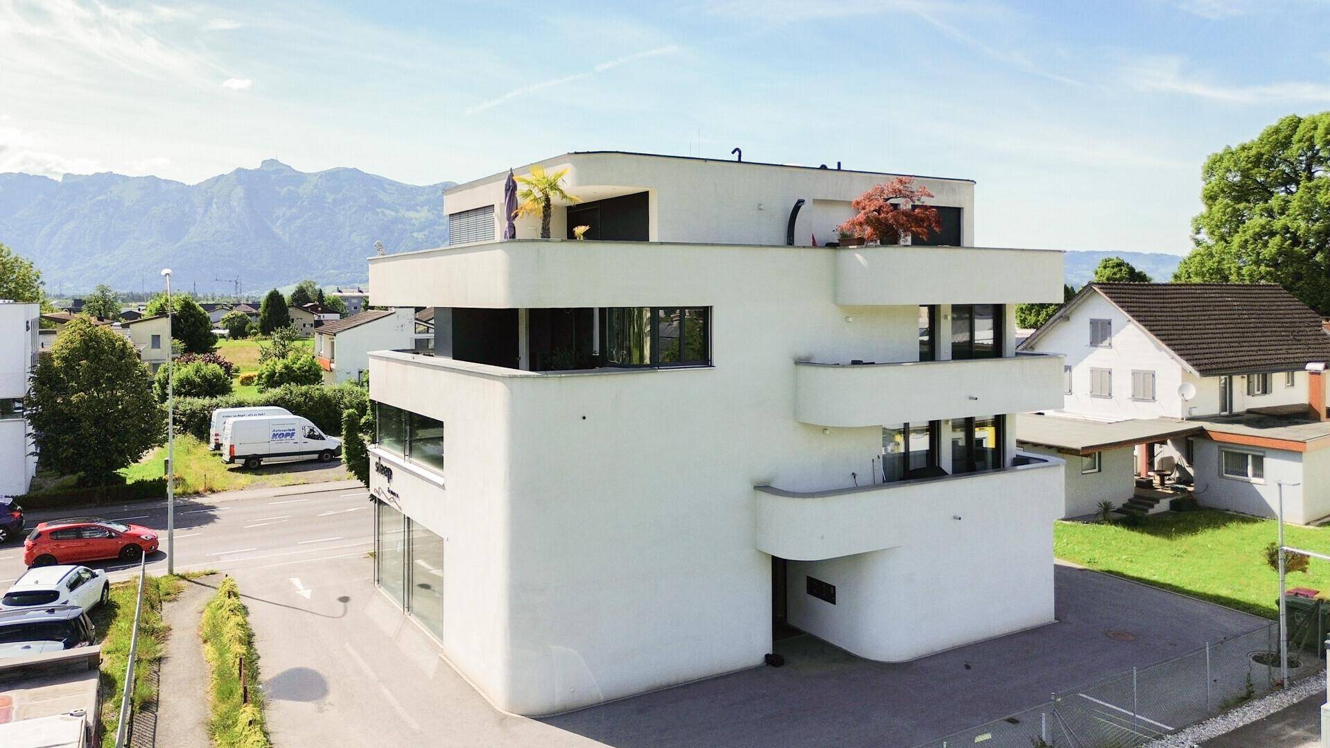 Elegantes, modernes Gebäude mit geschwungenen Balkonen und Panoramablick auf die Berge.