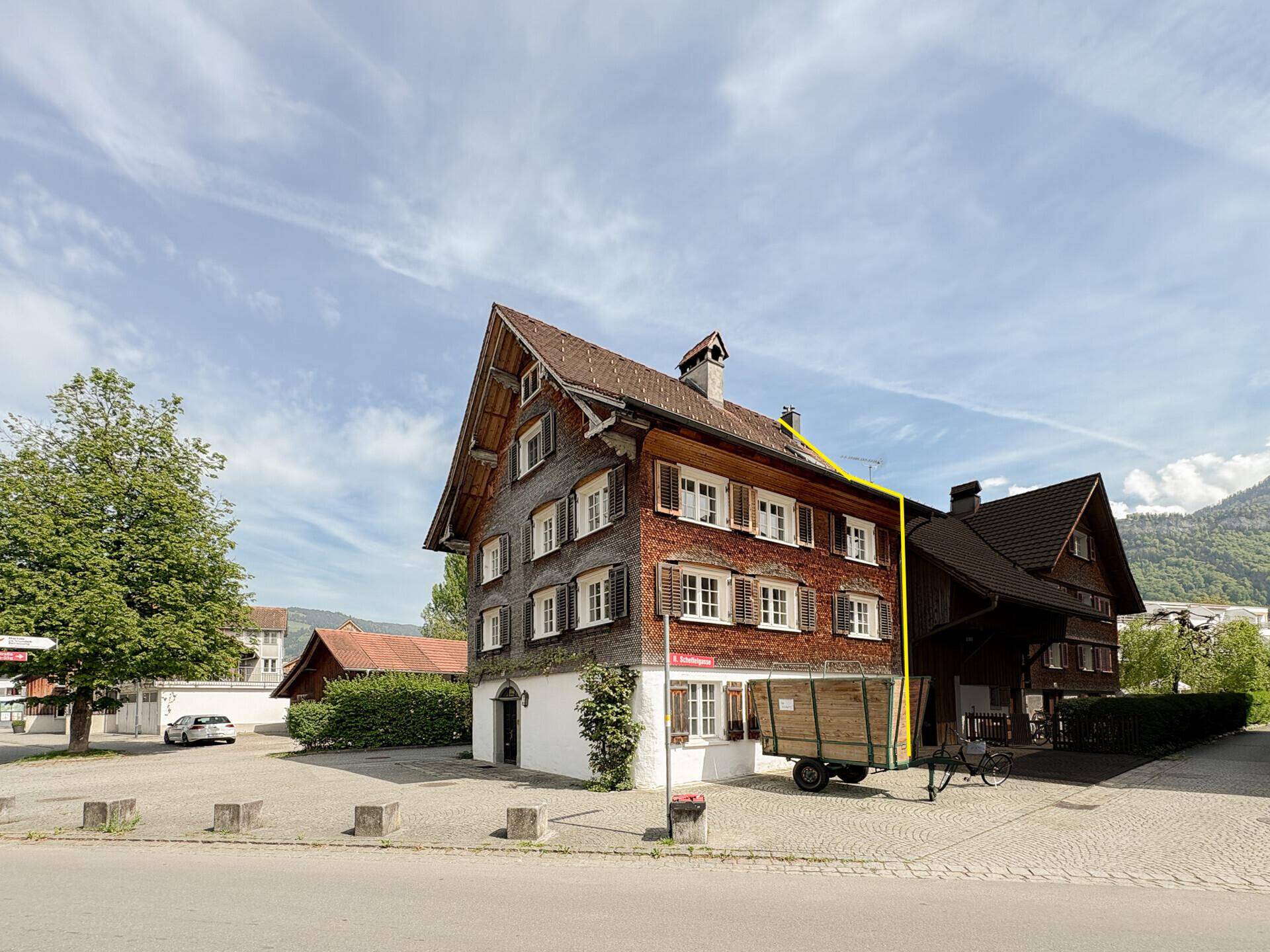 Traditionelles Holzhaus mit Satteldach und umliegender Bebauung.