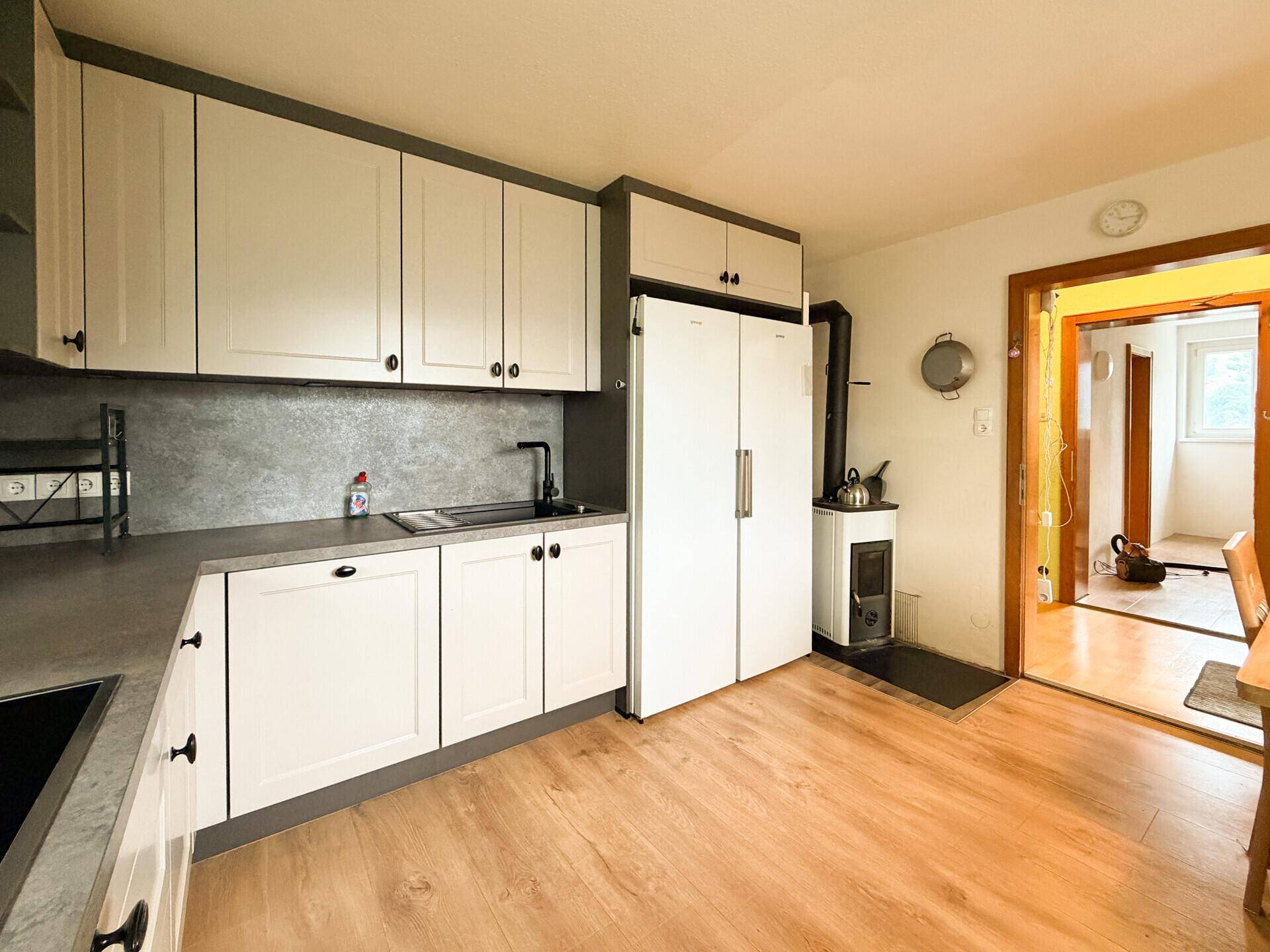 Funktionale Küche mit Spülbereich, großem Kühlschrank und einem gemütlichen Holzofen.