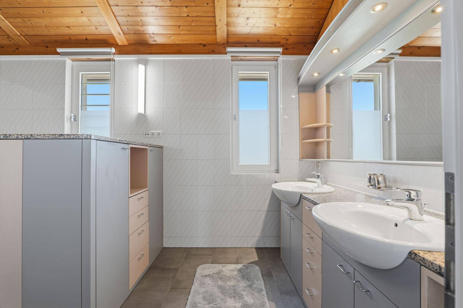 Geräumiges Badezimmer mit Doppelwaschbecken, Granit-Arbeitsplatten und Holzdecke.