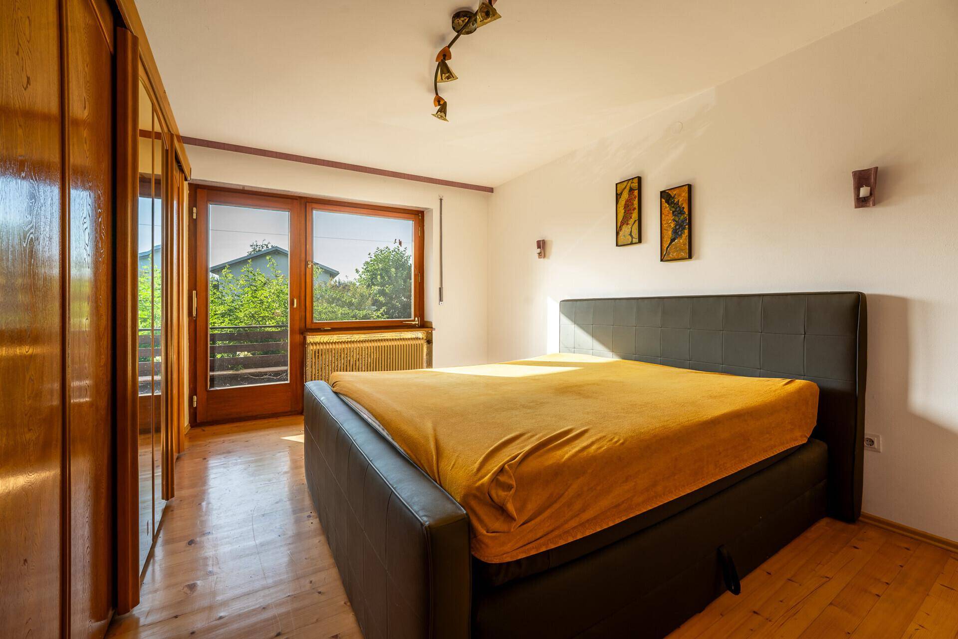 Schlafzimmer mit Holzboden, großem Bett und direktem Zugang zu einem Balkon.