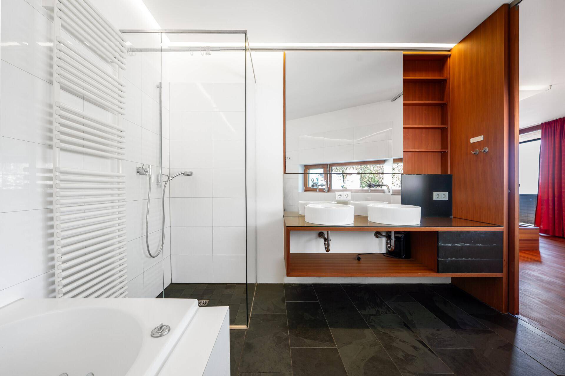 Elegantes Badezimmer mit Glasdusche, Doppelwaschbecken und großem Spiegel.
