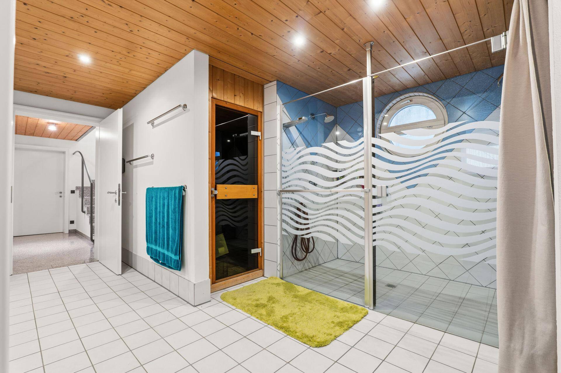 Wellnessbereich mit großer Dusche, Sauna und Fliesenboden für Erholung.