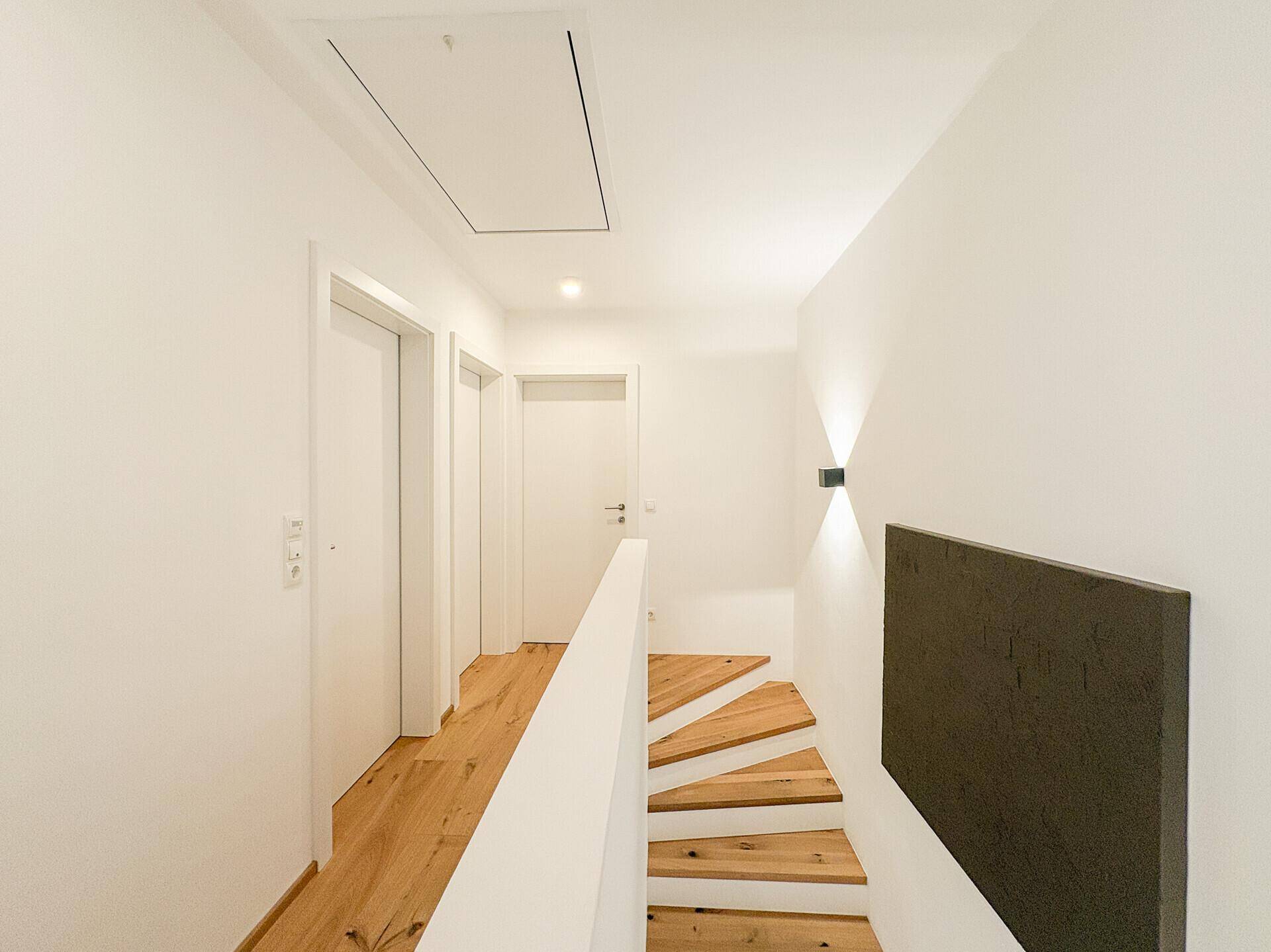 Heller Flur mit Holztreppe, Holzboden und Zugang zu den oberen Zimmern.