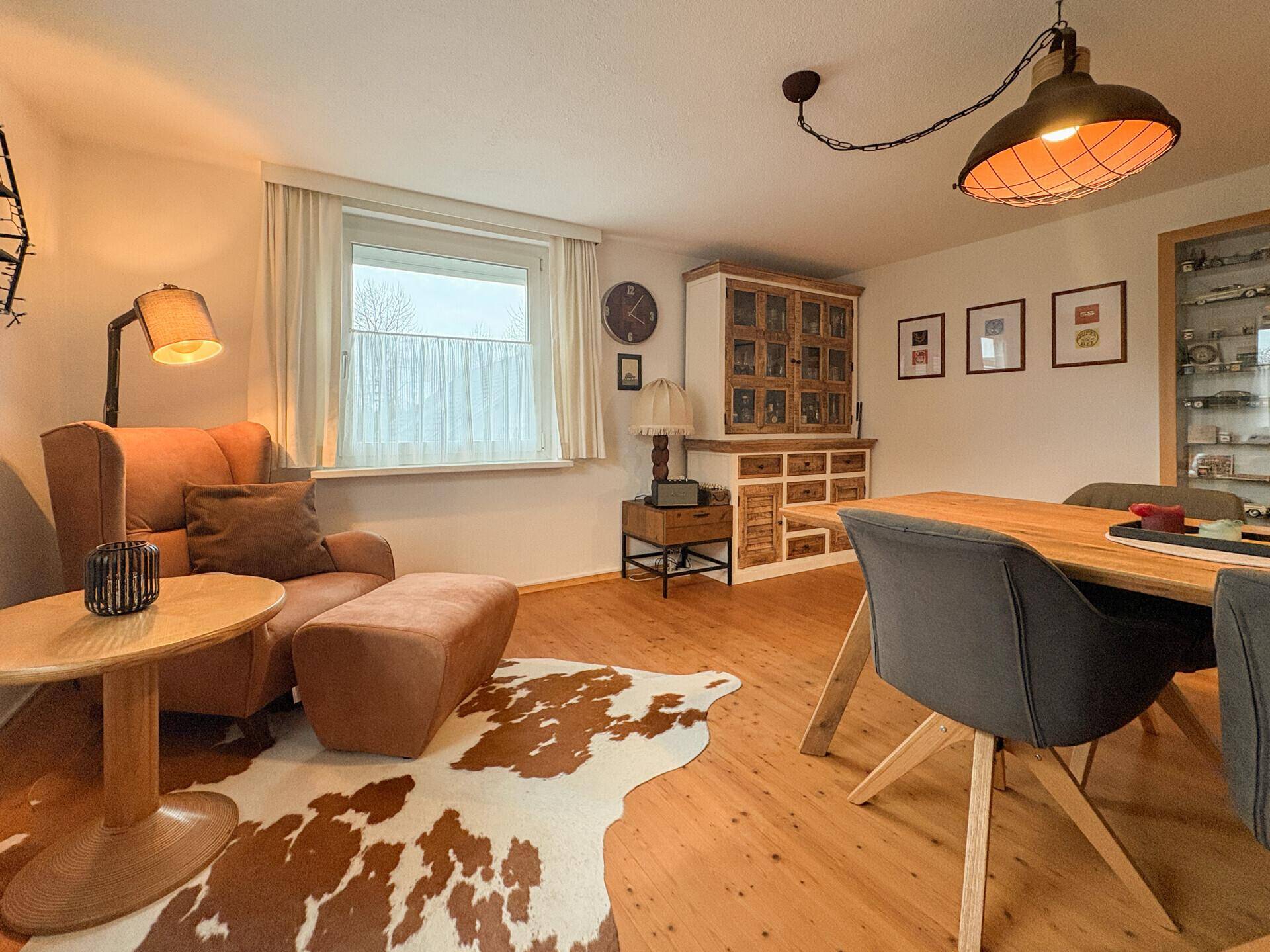 Essbereich mit Holztisch, modernen Stühlen und gemütlichem Sessel auf Holzboden.
