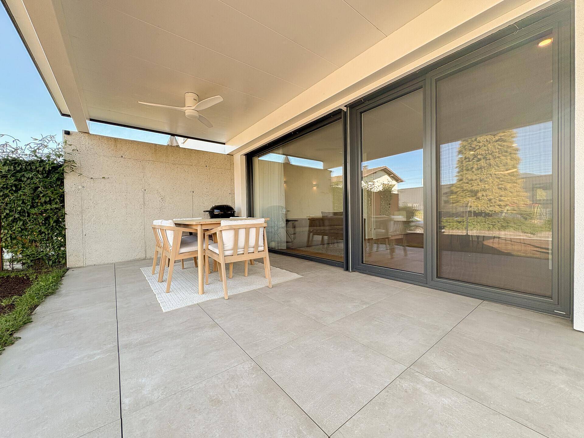 Überdachte Terrasse mit modernen Gartenmöbeln und großzügigen Schiebetüren zum Wohnbereich.