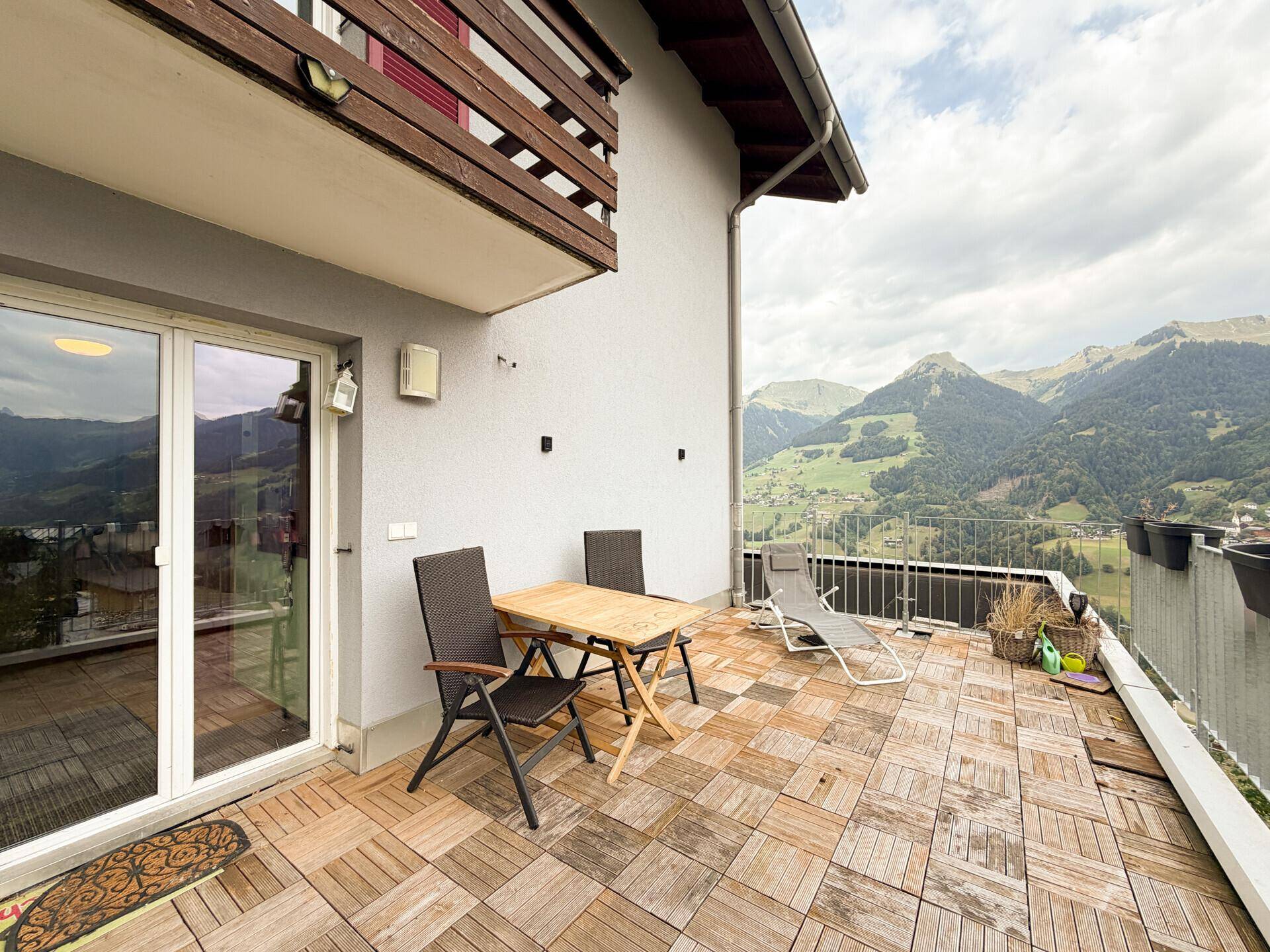 Große Terrasse mit Holzboden, Sitzgelegenheiten und einem atemberaubenden Bergblick.