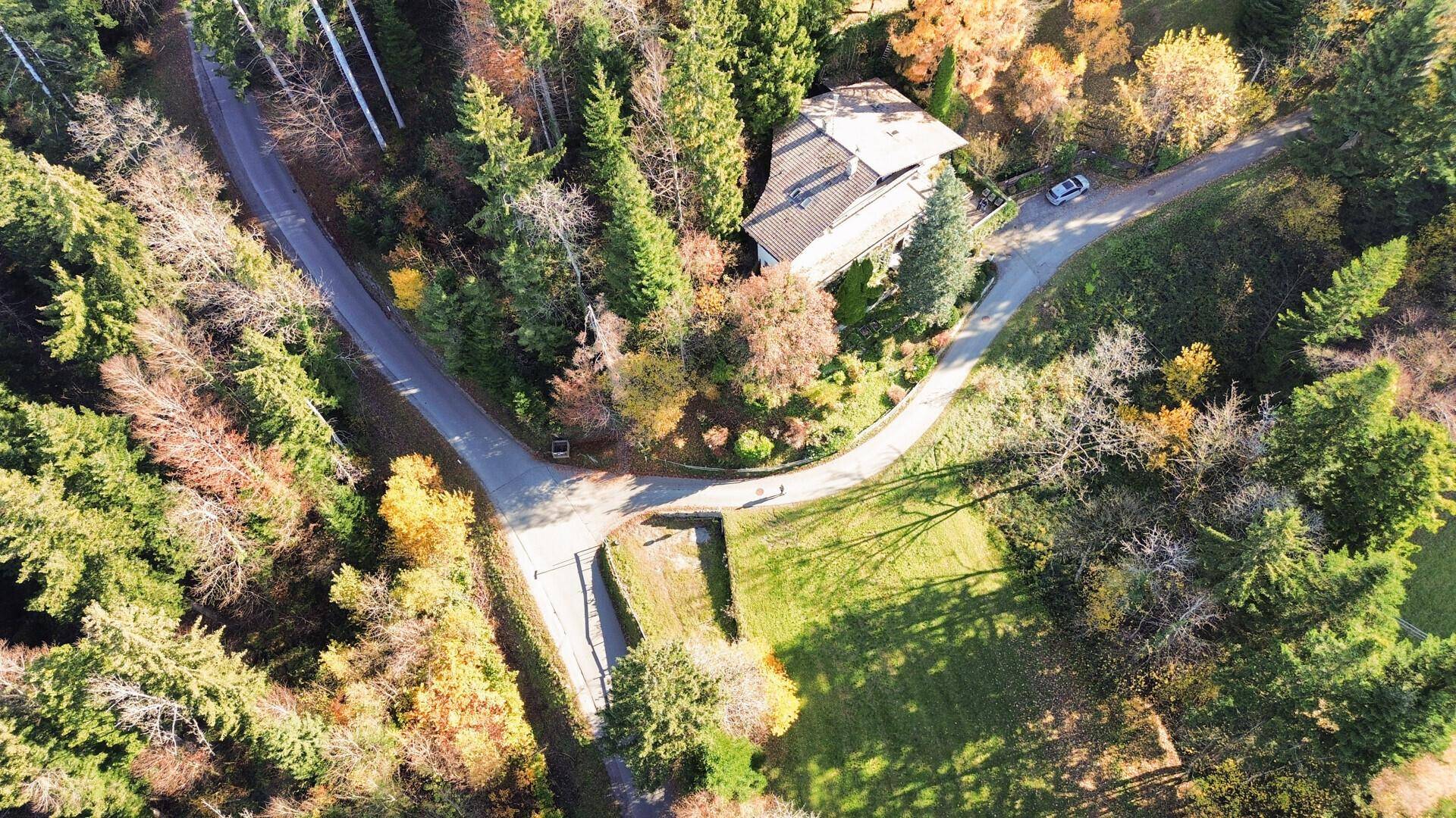 Weitläufige Luftaufnahme der bewaldeten Landschaft mit Straßen und einem Gebäude im Hintergrund.