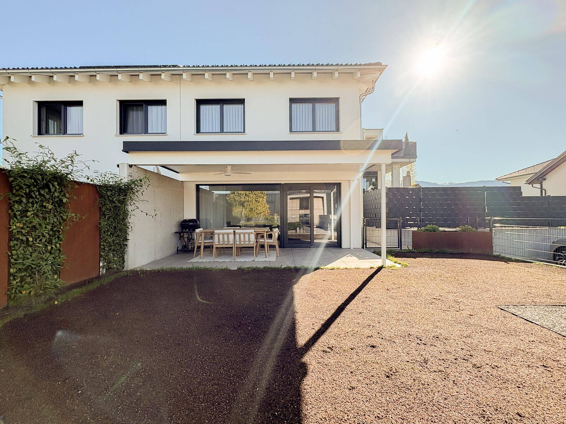 Sonnige Rückseite des Hauses mit Terrasse und Garten, ideal für Entspannung im Freien.