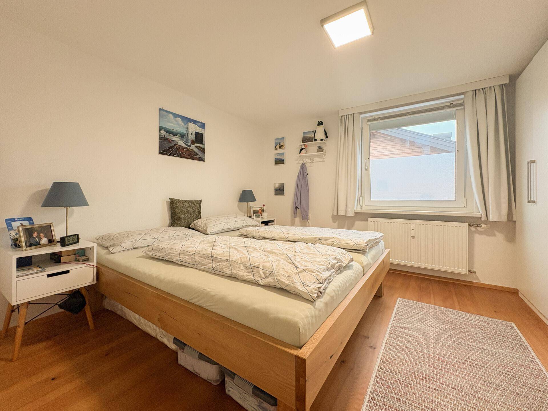 Schlafzimmer mit Doppelbett, Holzboden und Fenster für natürliches Licht.