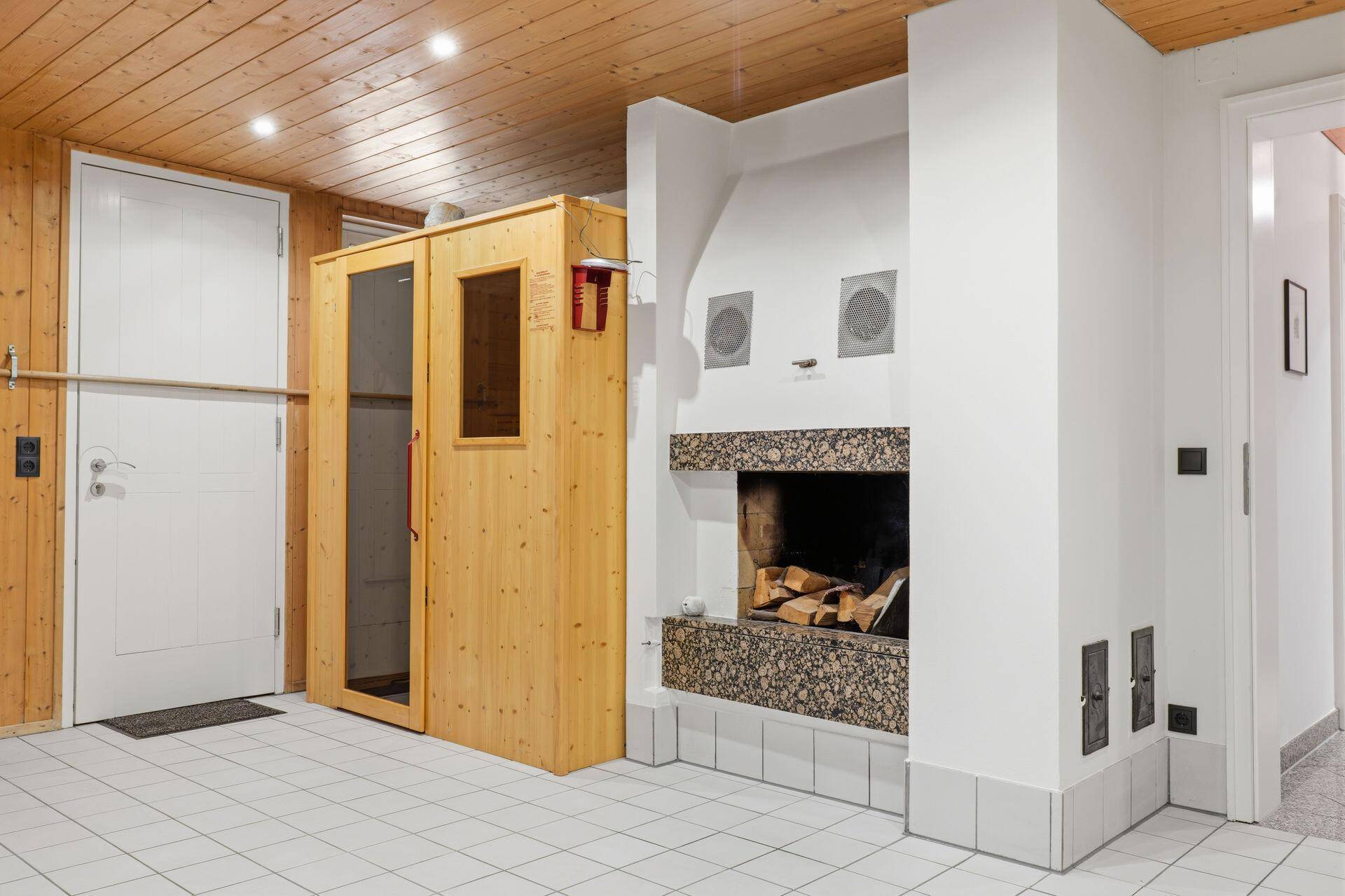Wellnessbereich mit Sauna, Kamin und Fliesenboden für gemütliche Stunden.