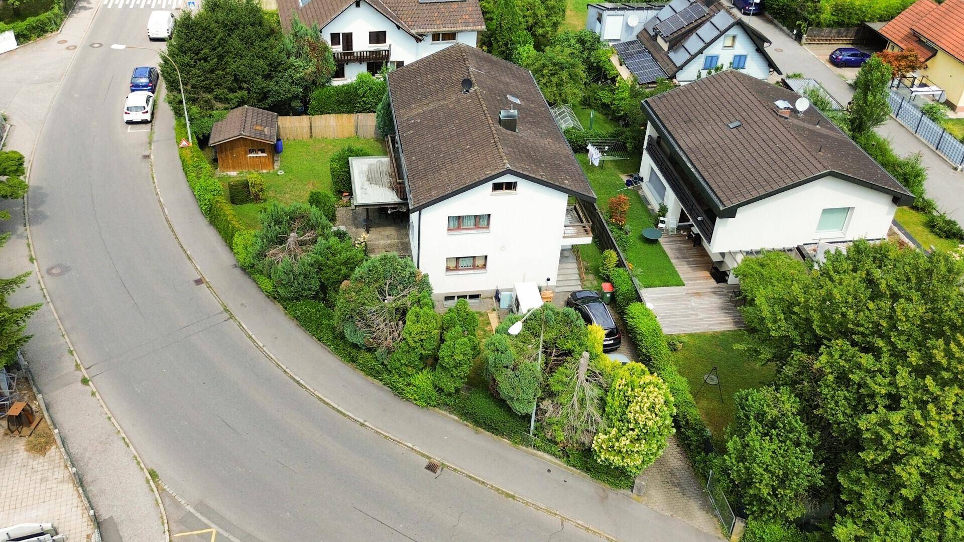 Übersicht aus der Luft zeigt das Einfamilienhaus mit Grundstück und angrenzender Straße.