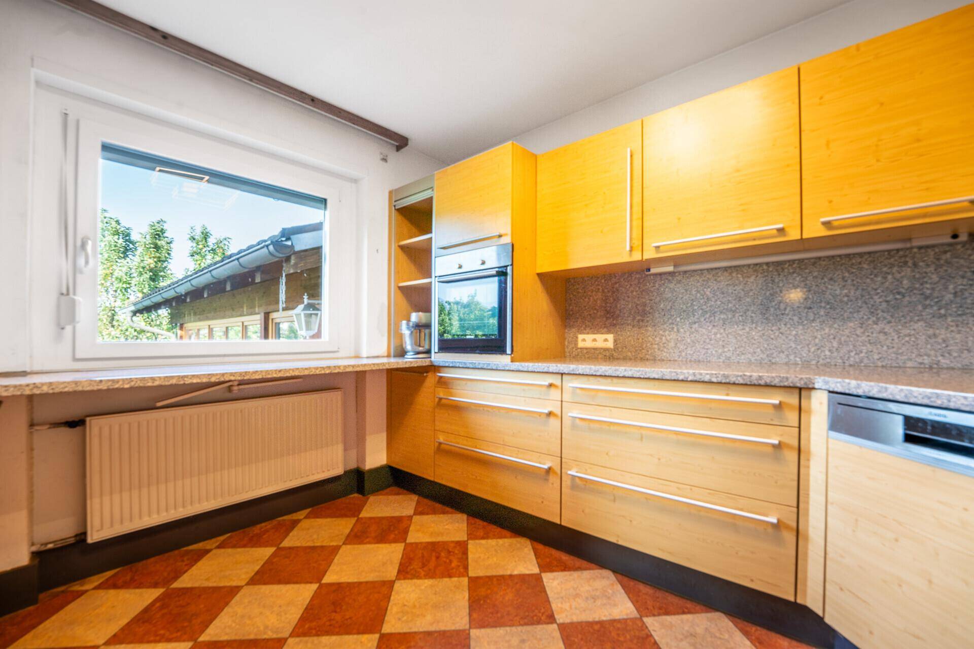 Helle Küche mit Holzfronten, Fenster und Heizkörper, ideal für den täglichen Gebrauch.
