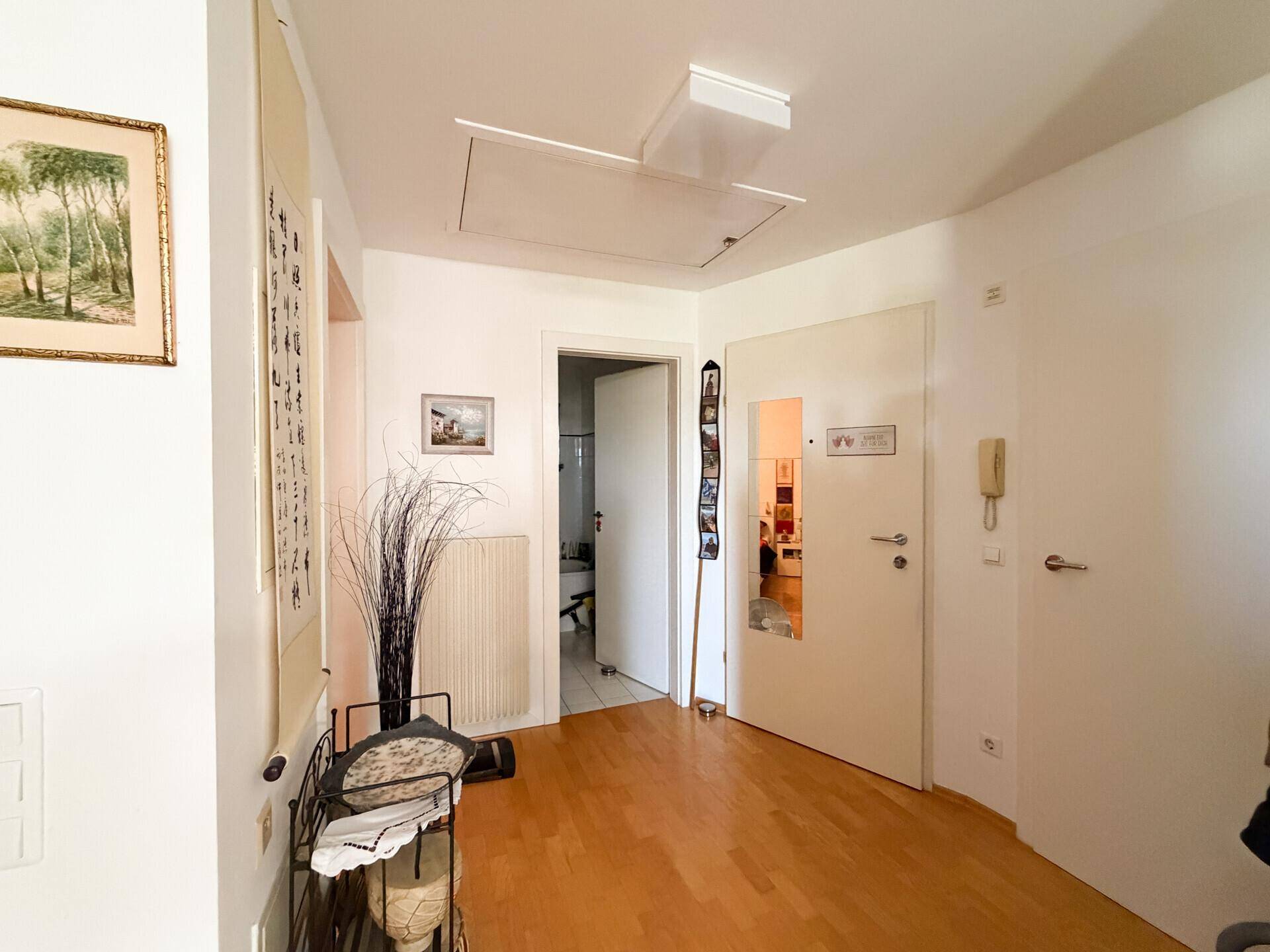 Heller Flur mit Holzboden und Zugang zu weiteren Räumen der Wohnung.