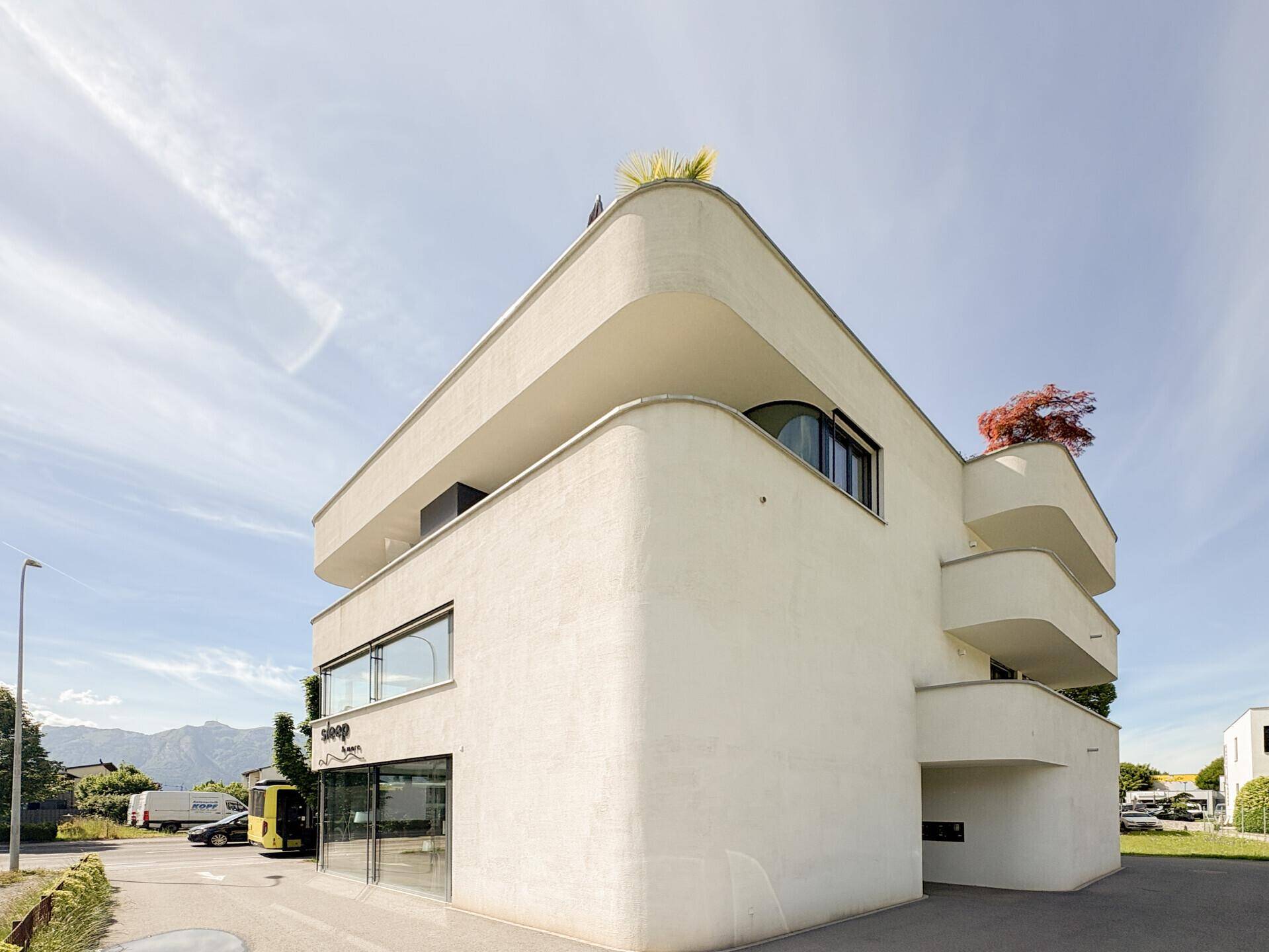 Markante moderne Architektur des Gebäudes mit abgerundeten Ecken und großen Fensterfronten.