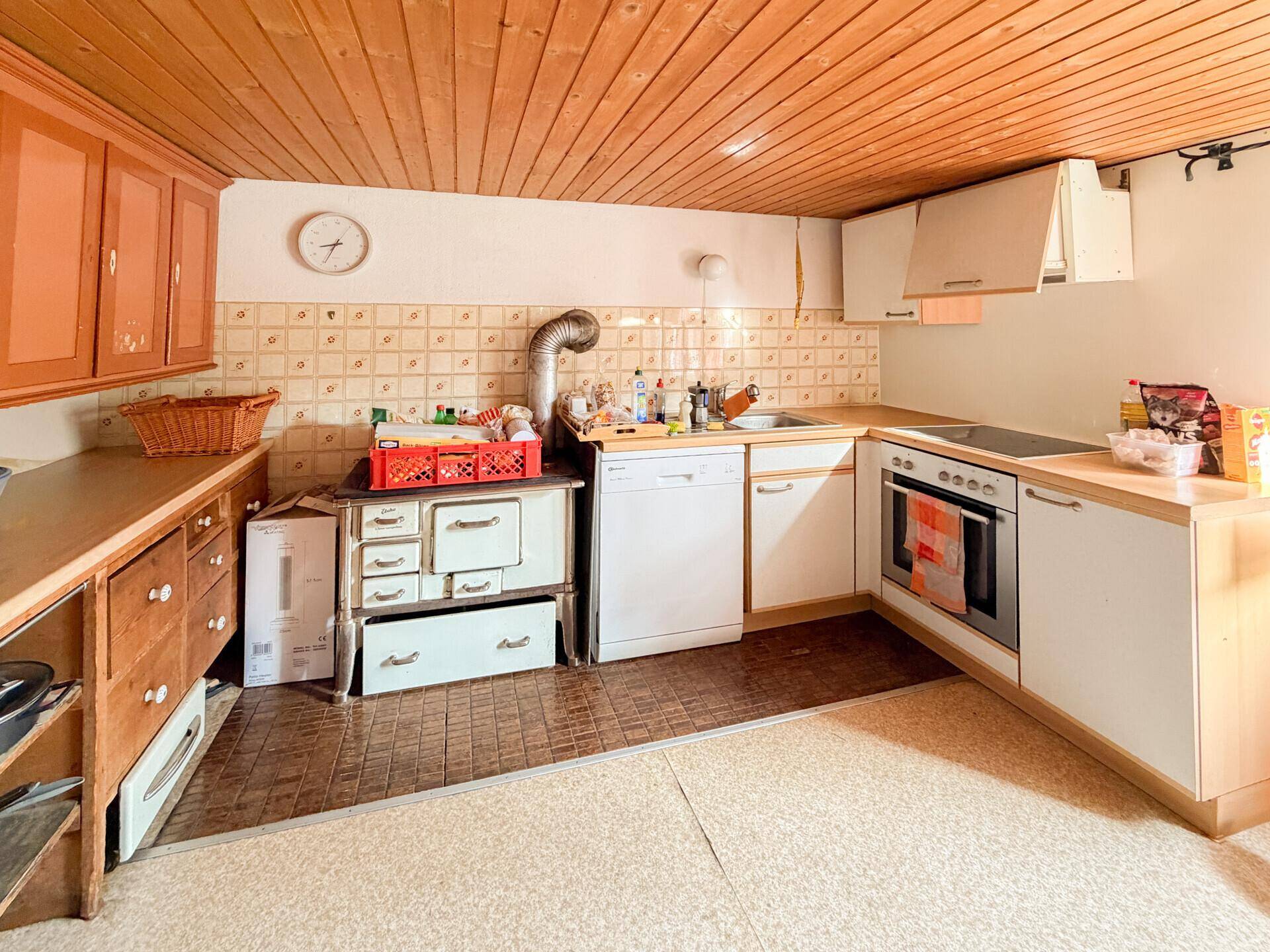 Rustikale Küche mit Holzelementen, einem traditionellen Holzofen und modernen Einbaugeräten.