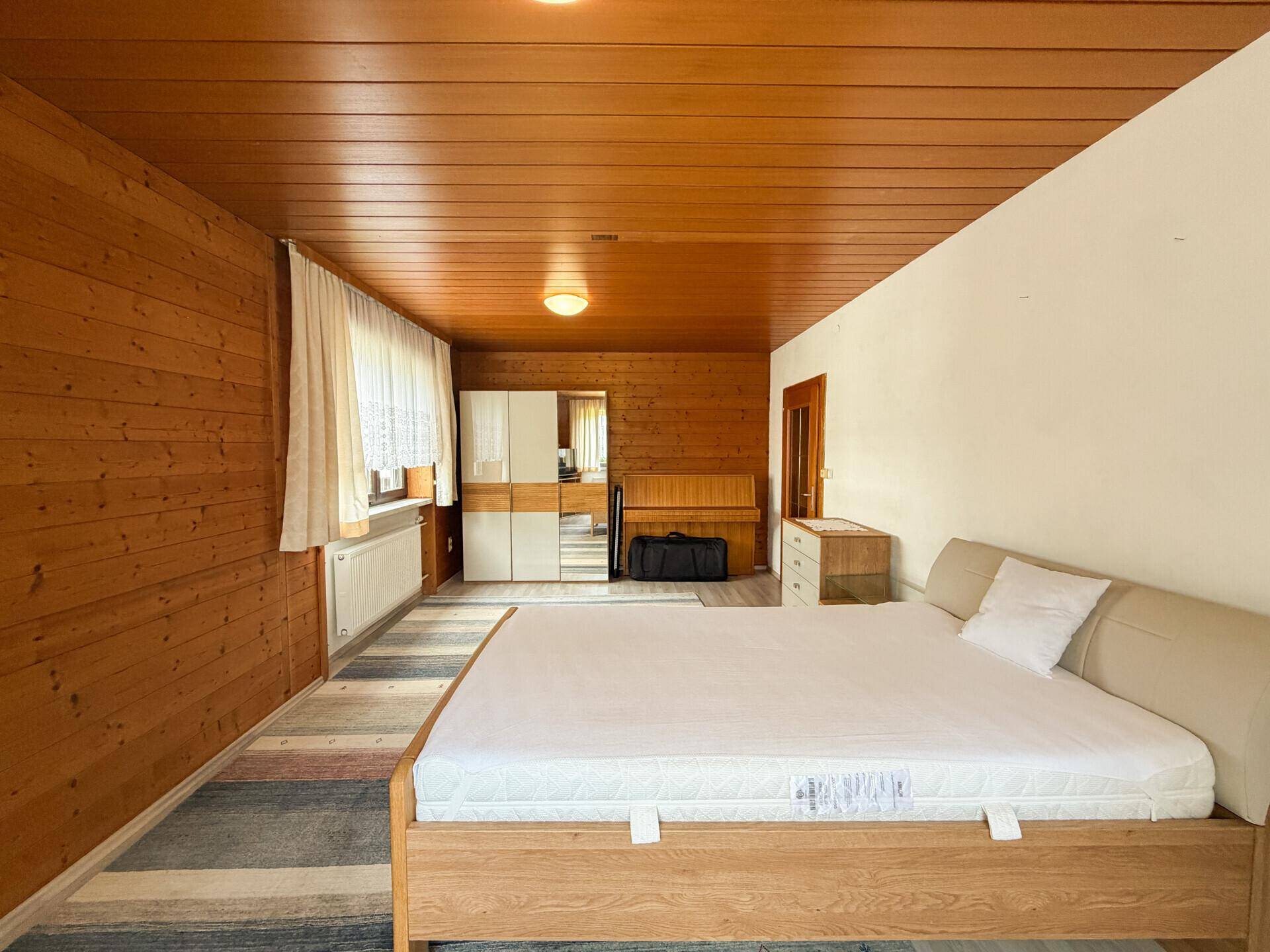Geräumiges Schlafzimmer mit Holzdecke, Holzwand und einem großen Bett.
