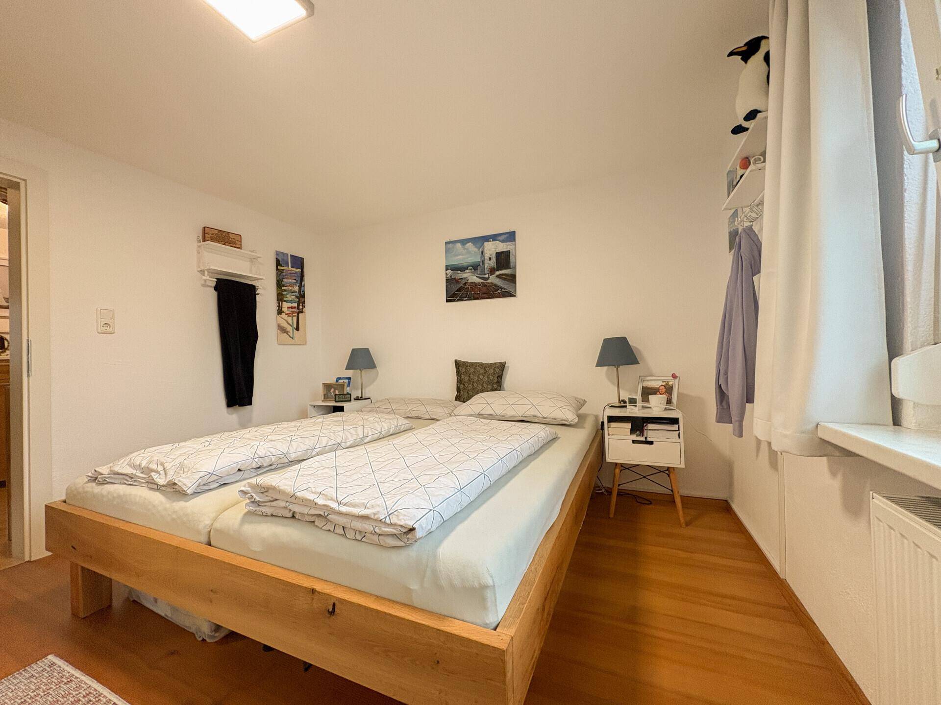 Gemütliches Schlafzimmer mit Holzbett, Nachttischen und hellem Holzboden.