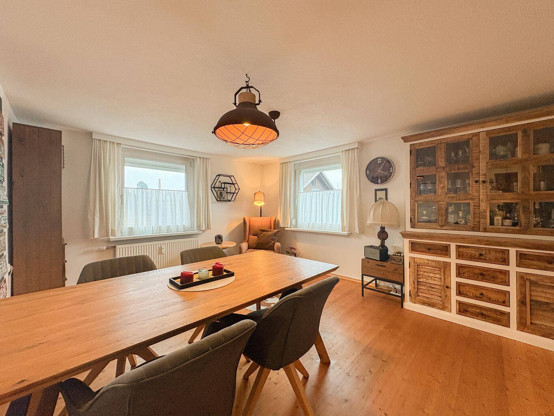 Geräumiges Esszimmer mit großem Holztisch, rustikalem Schrank und gemütlicher Leseecke.