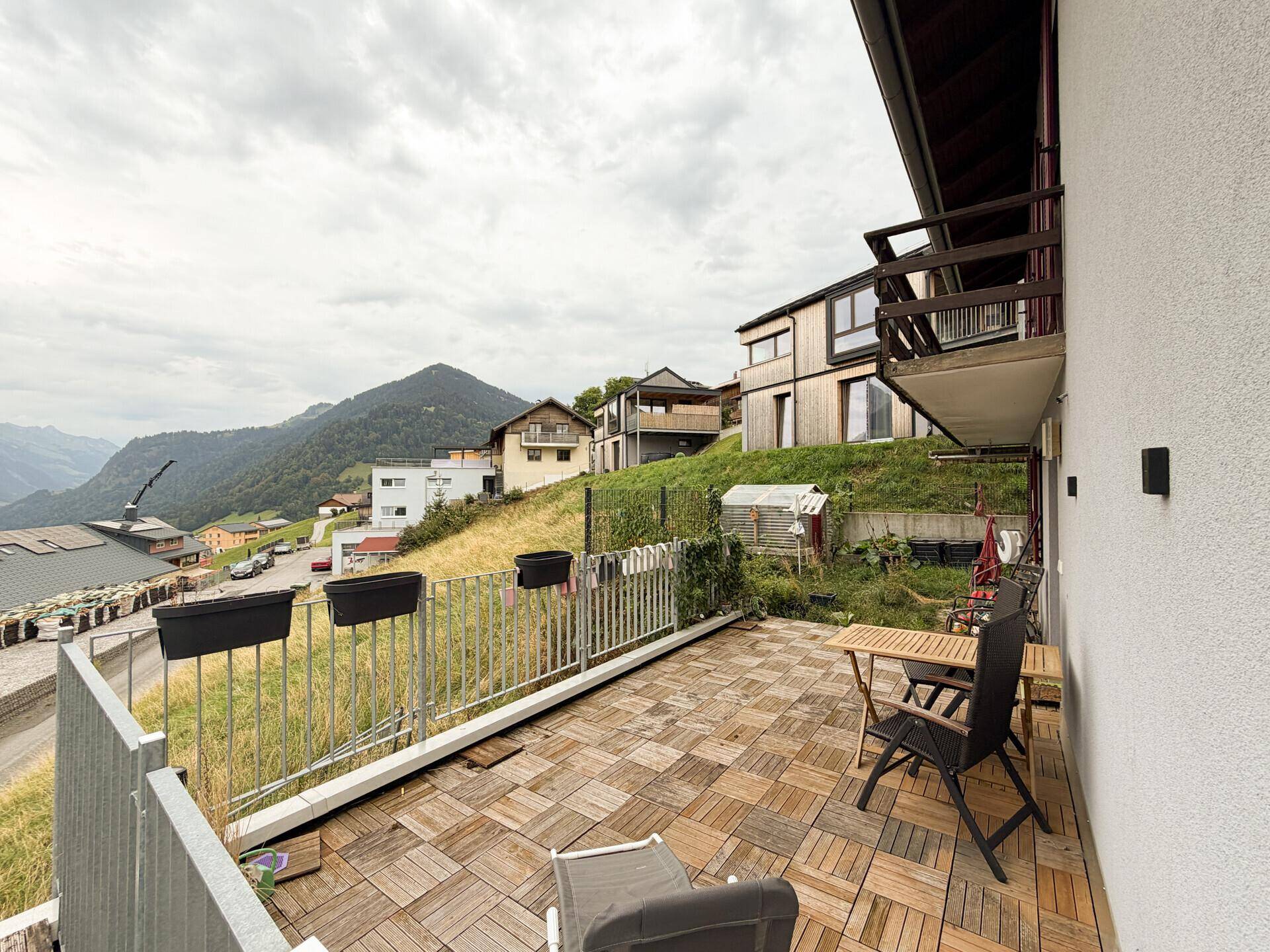 Weitläufige Terrasse mit Panoramablick auf die umliegende Berglandschaft und Nachbarhäuser.