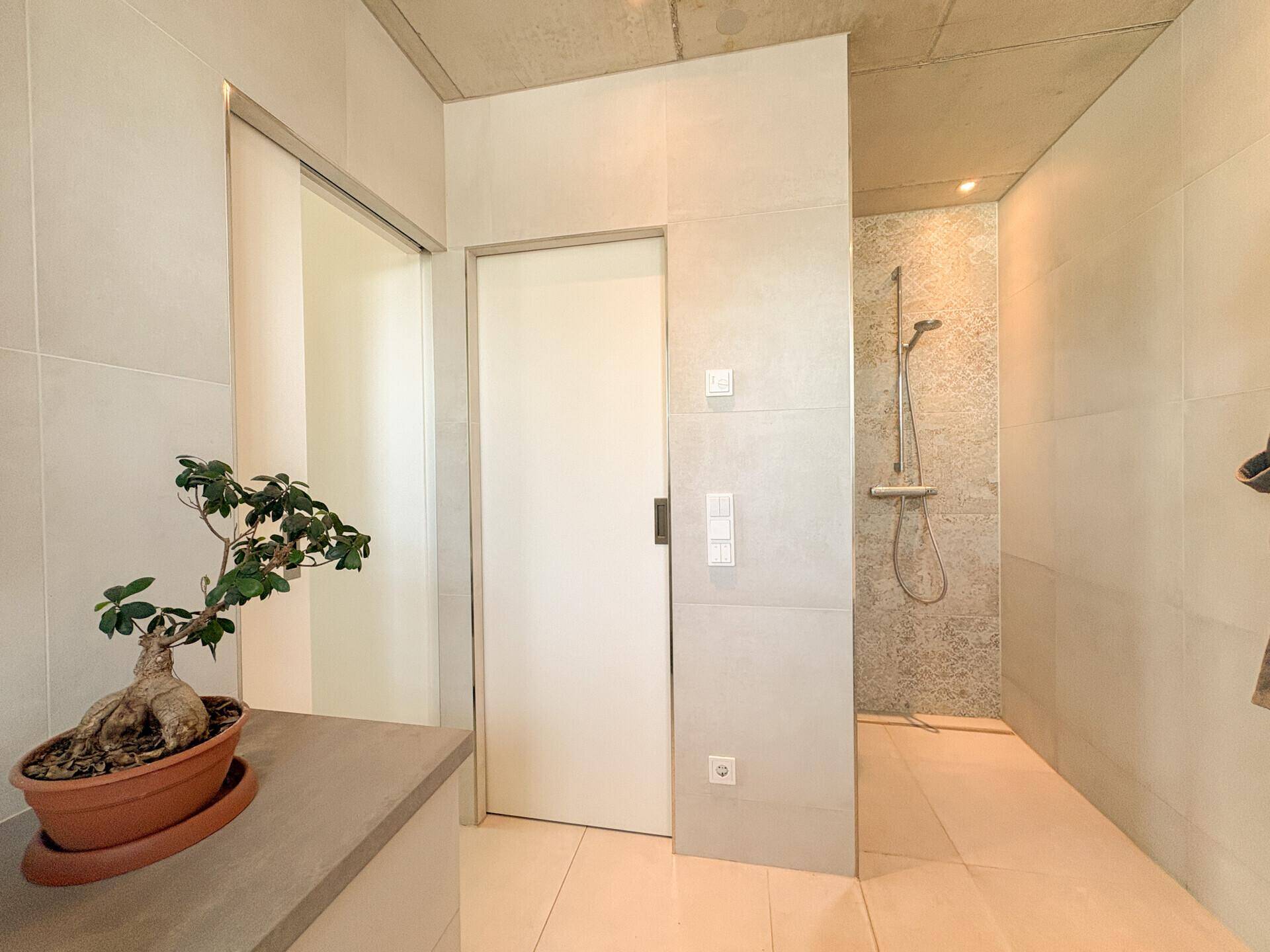 Modernes Badezimmer mit ebenerdiger Dusche, Fliesenboden und minimalistischem Design.