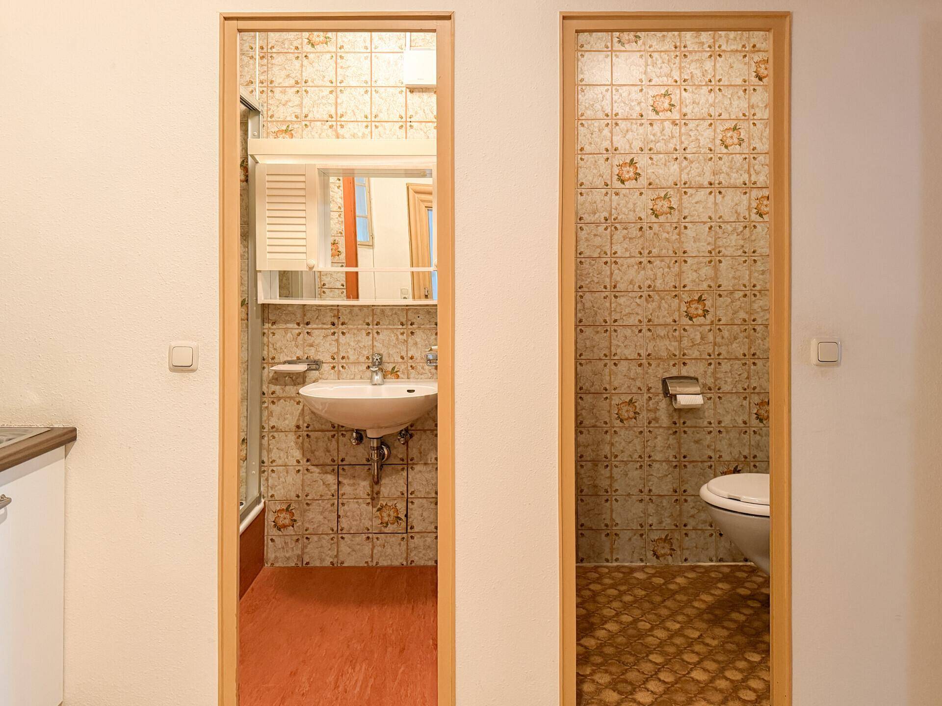 Zwei Türen führen zu einem Badezimmer mit Dusche und einem separaten WC.