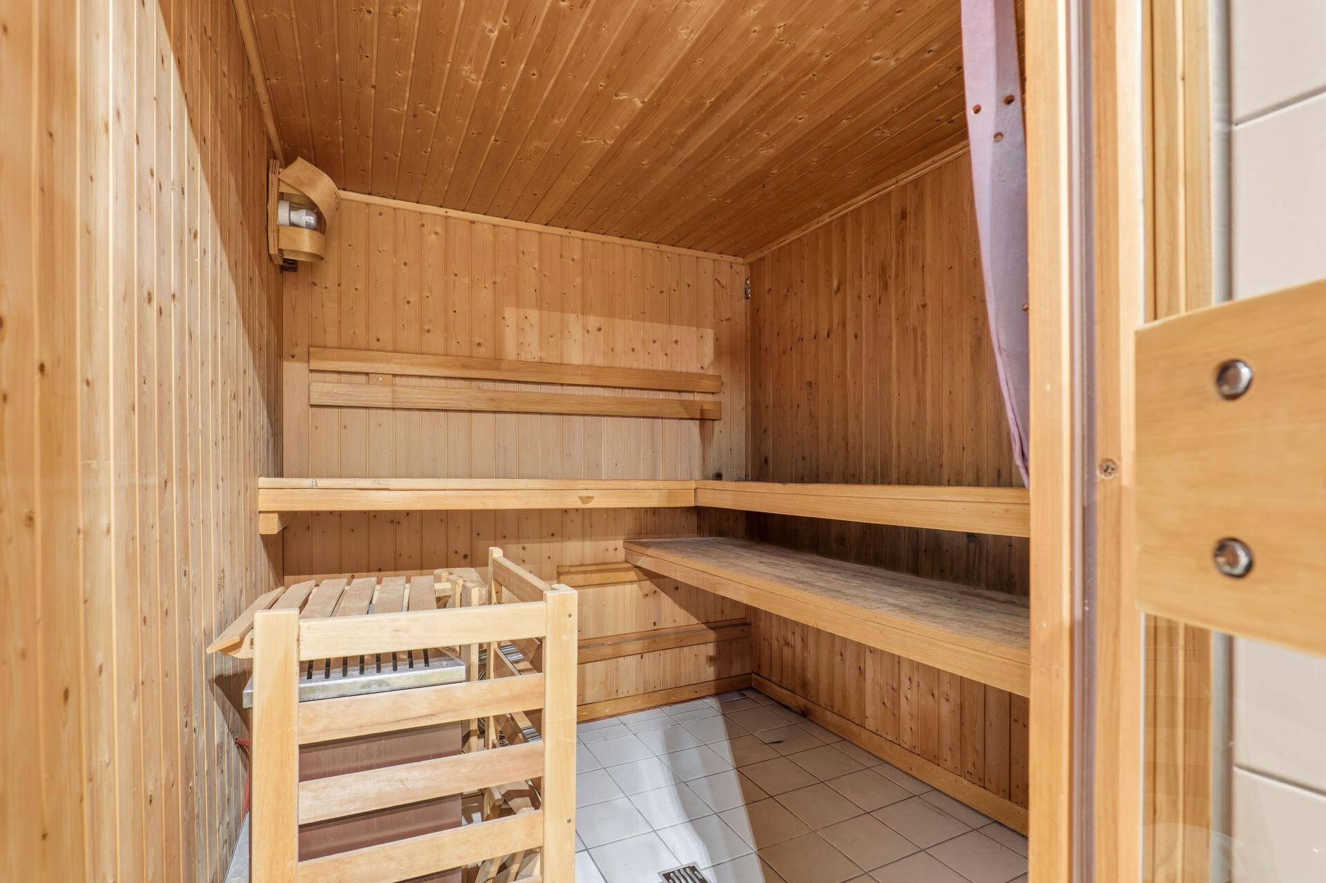 Holzvertäfelte Sauna mit Bänken und Saunaofen für entspannende Momente.