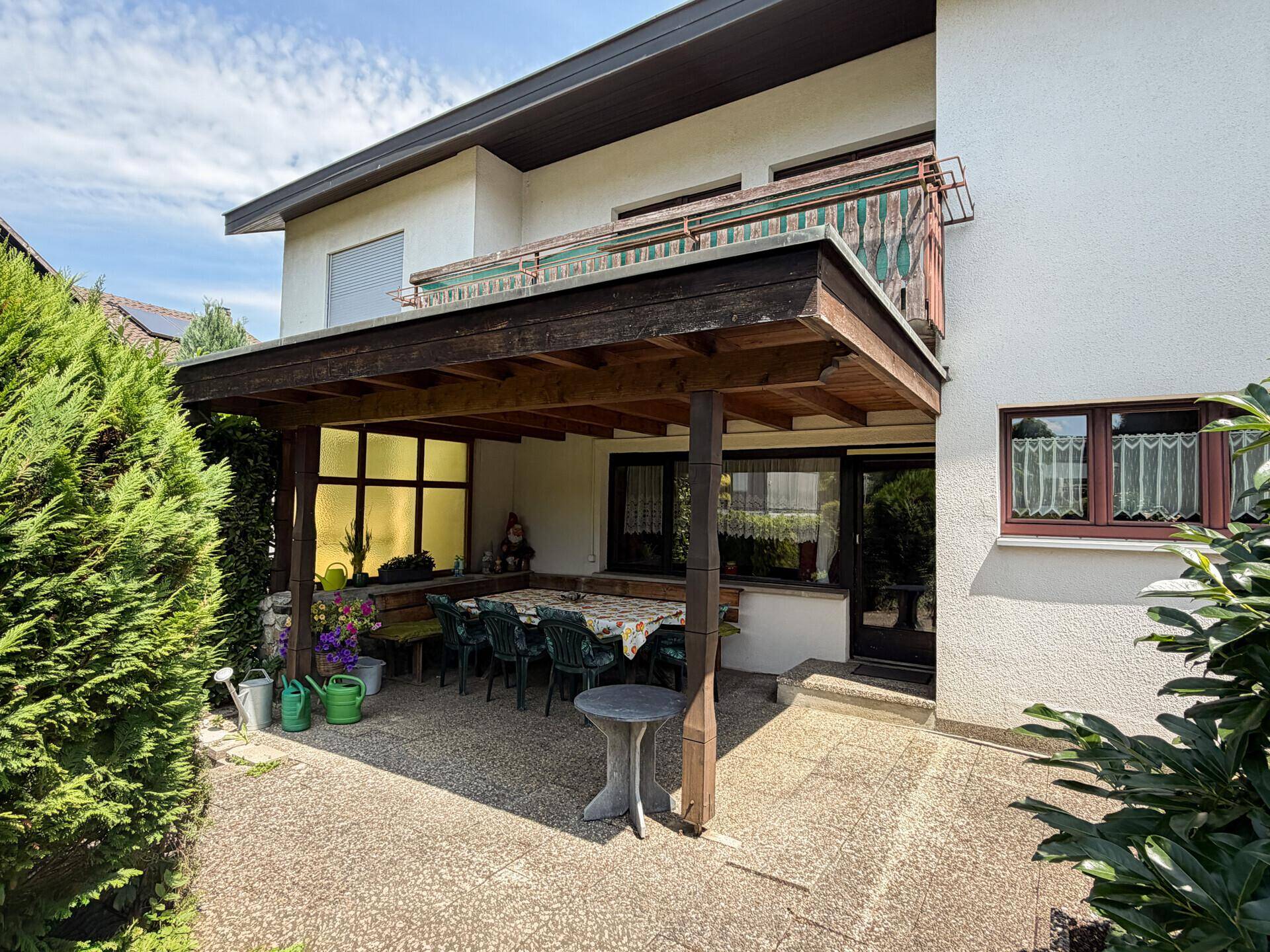Überdachte Terrasse mit Esstisch und Stühlen, ideal für Mahlzeiten im Freien.