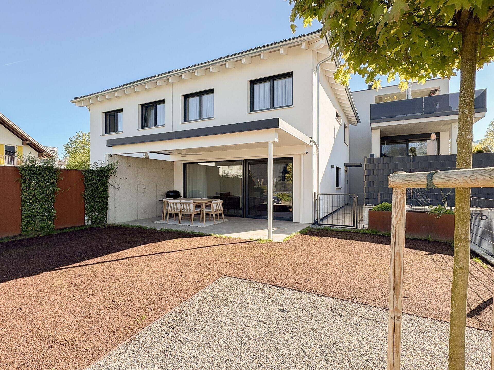 Rückansicht des modernen Hauses mit großer Terrasse und neu angelegtem Gartenbereich.