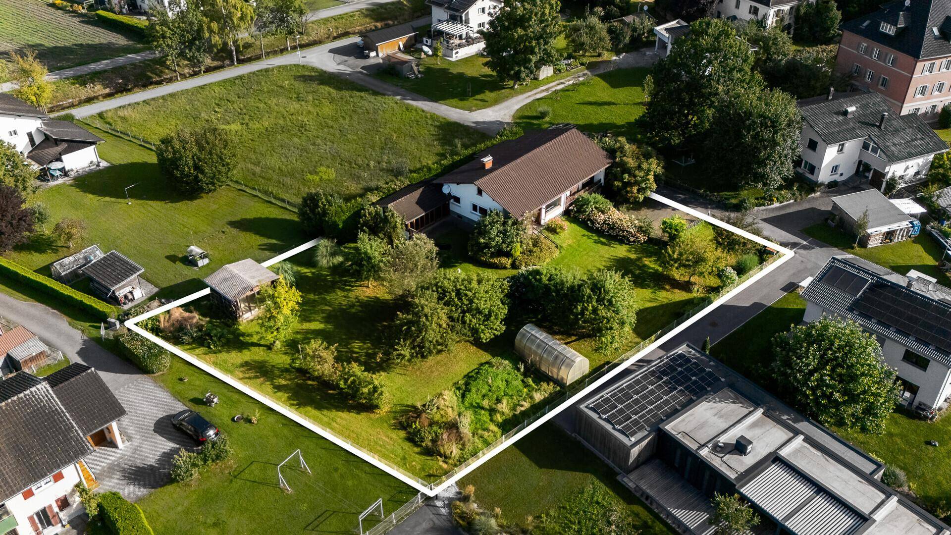 Luftaufnahme des Grundstücks mit umrandetem Bereich, großem Garten und Nebengebäuden.