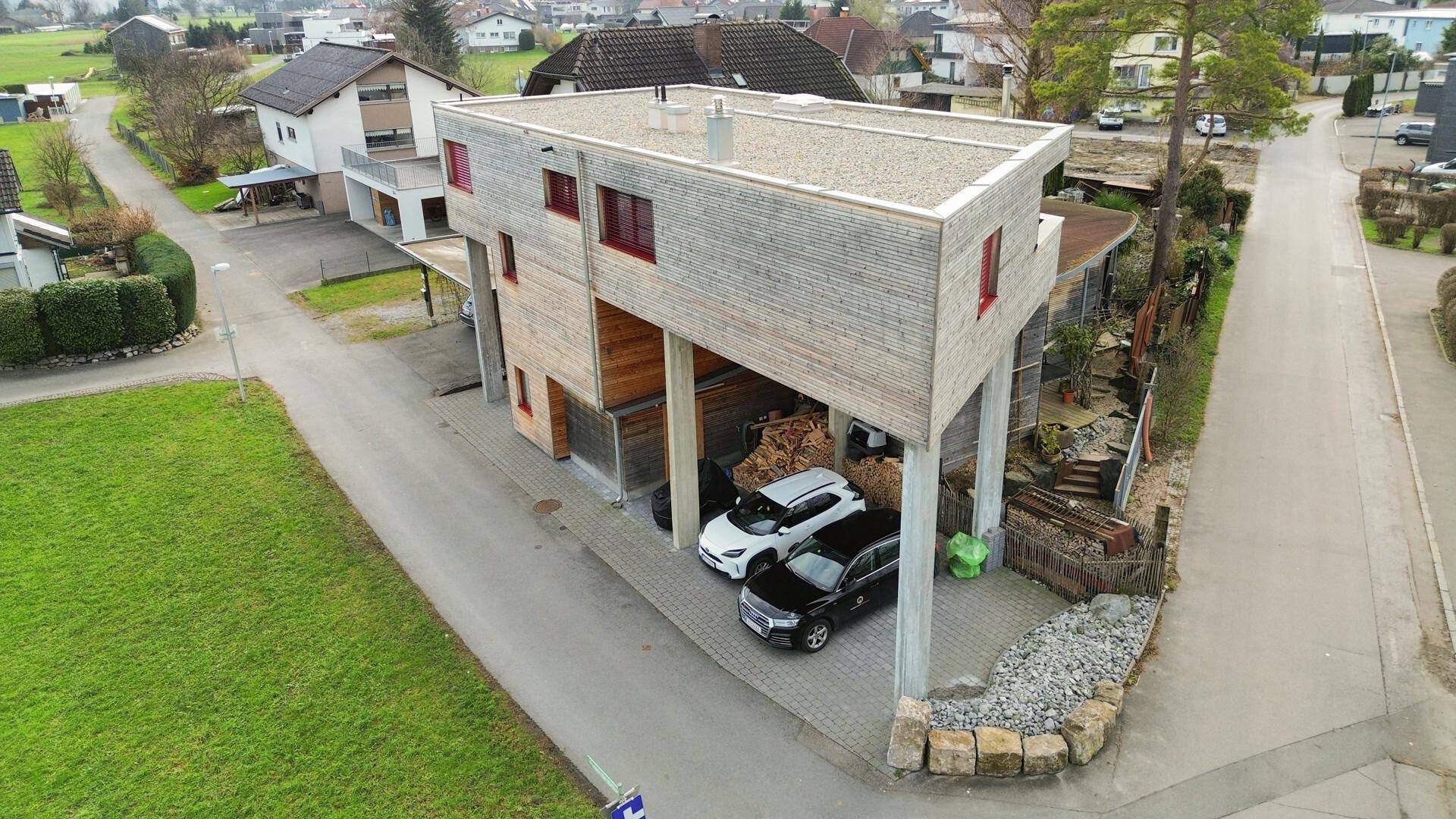Luftaufnahme des modernen Gebäudes mit Carport und Stellplätzen für Fahrzeuge.