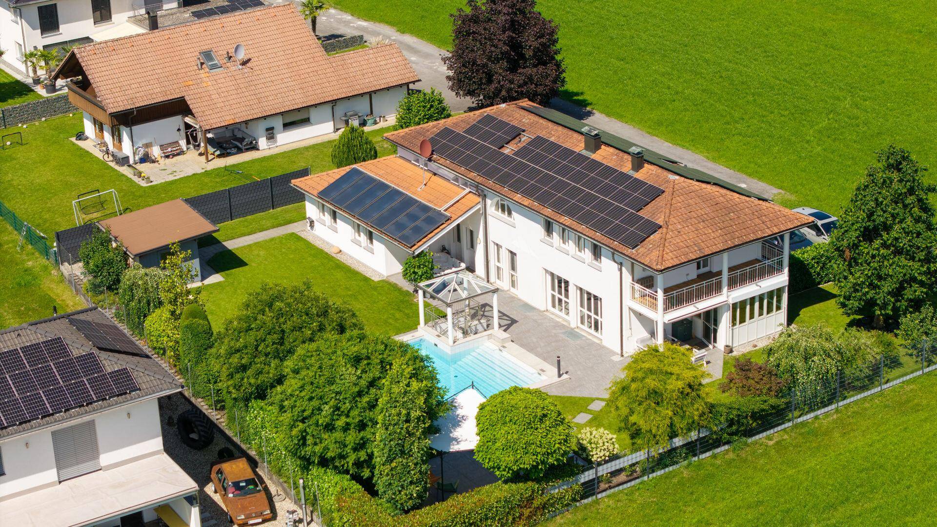 Luftaufnahme des Anwesens mit großem Garten, Swimmingpool und Photovoltaikanlagen auf den Dächern.