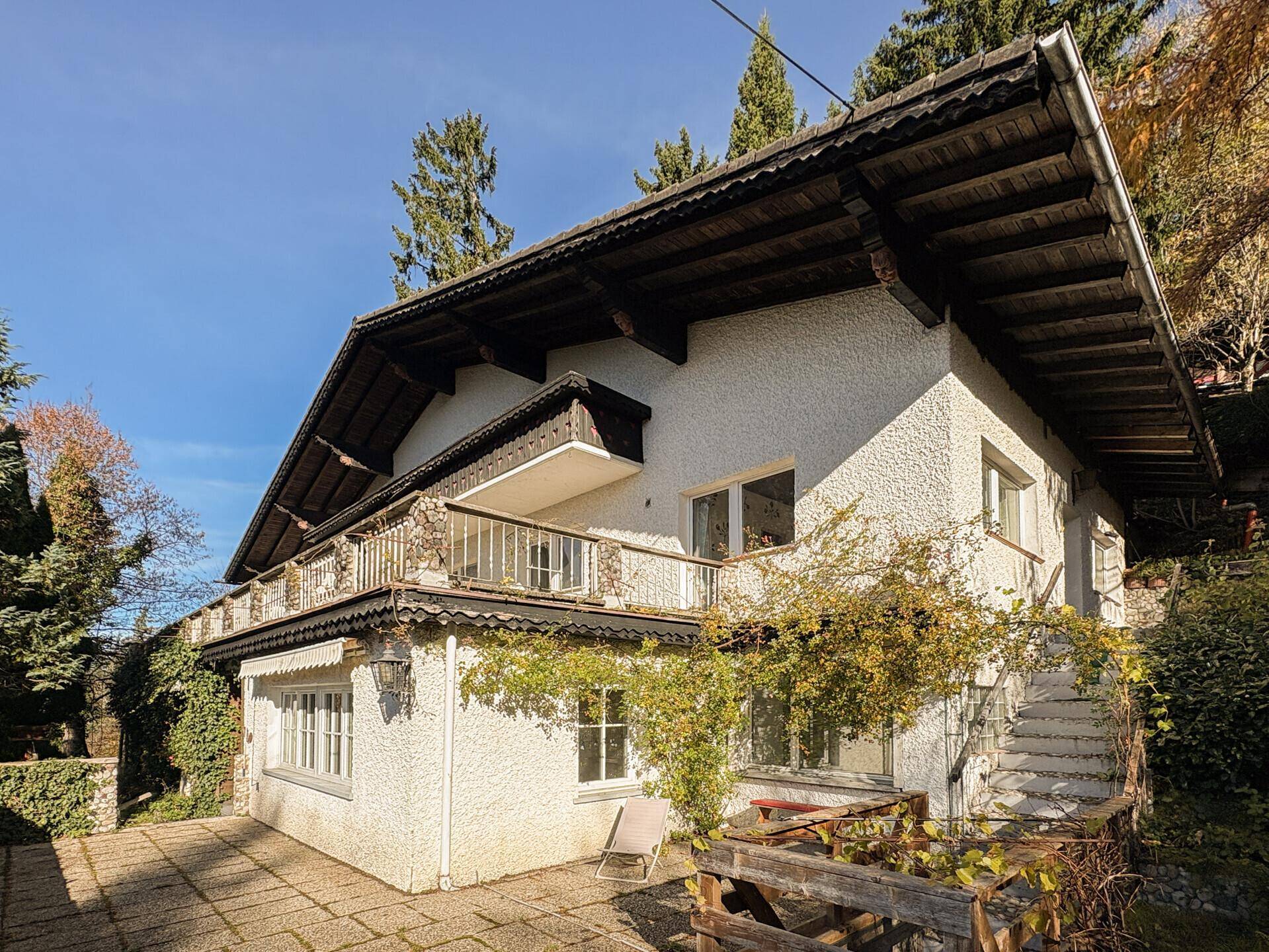 Seitliche Ansicht des Hauses mit einer gepflasterten Terrasse und Zugang zu einem Gartenbereich.