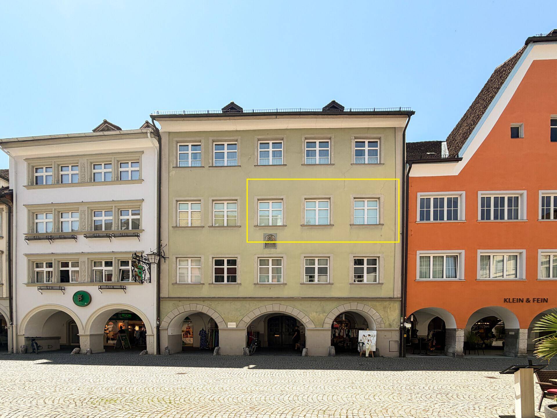 Historisches Gebäude mit traditioneller Fassade und vielen Fenstern an einem Stadtplatz.