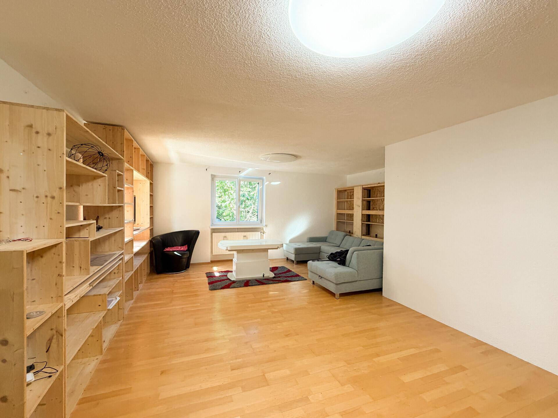 Helles Wohnzimmer mit Holzparkettboden und maßgefertigten Holzregalen, bietet viel Stauraum und eine gemütliche Atmosphäre.