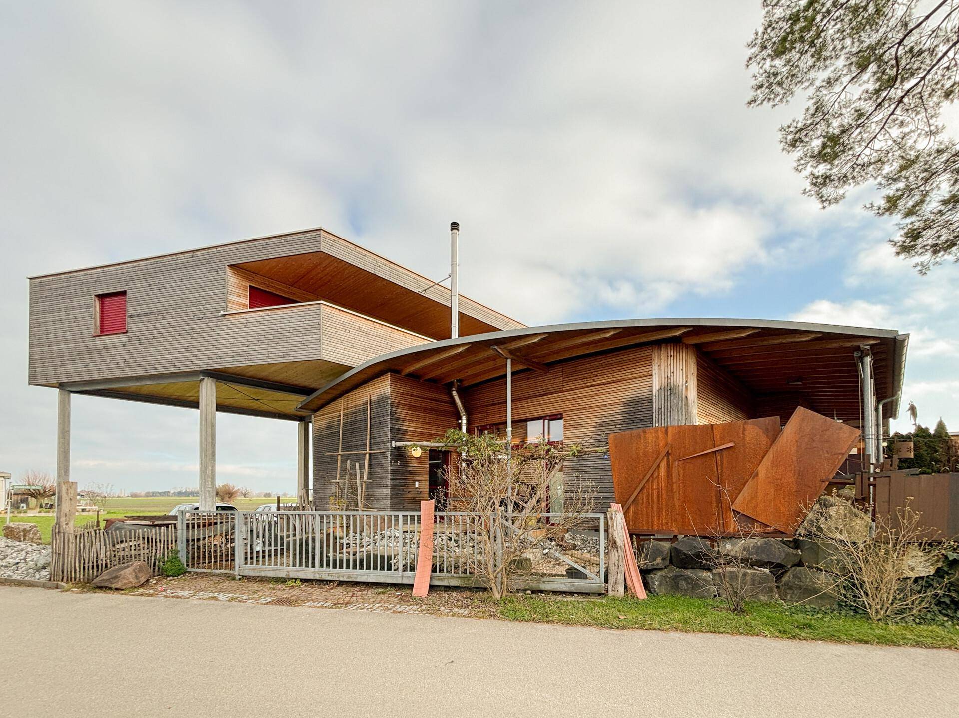 Moderne Holzfassade des Hauses mit geschwungenem Dach und einzigartiger Architektur.