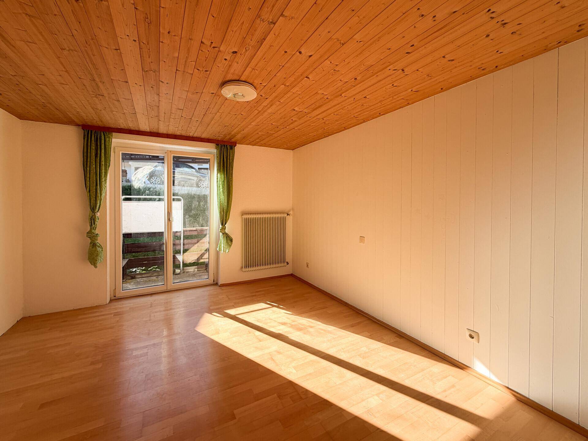 Raum mit Holzdecken und Parkettboden, bietet Zugang zu einem Balkon und viel natürliches Licht.