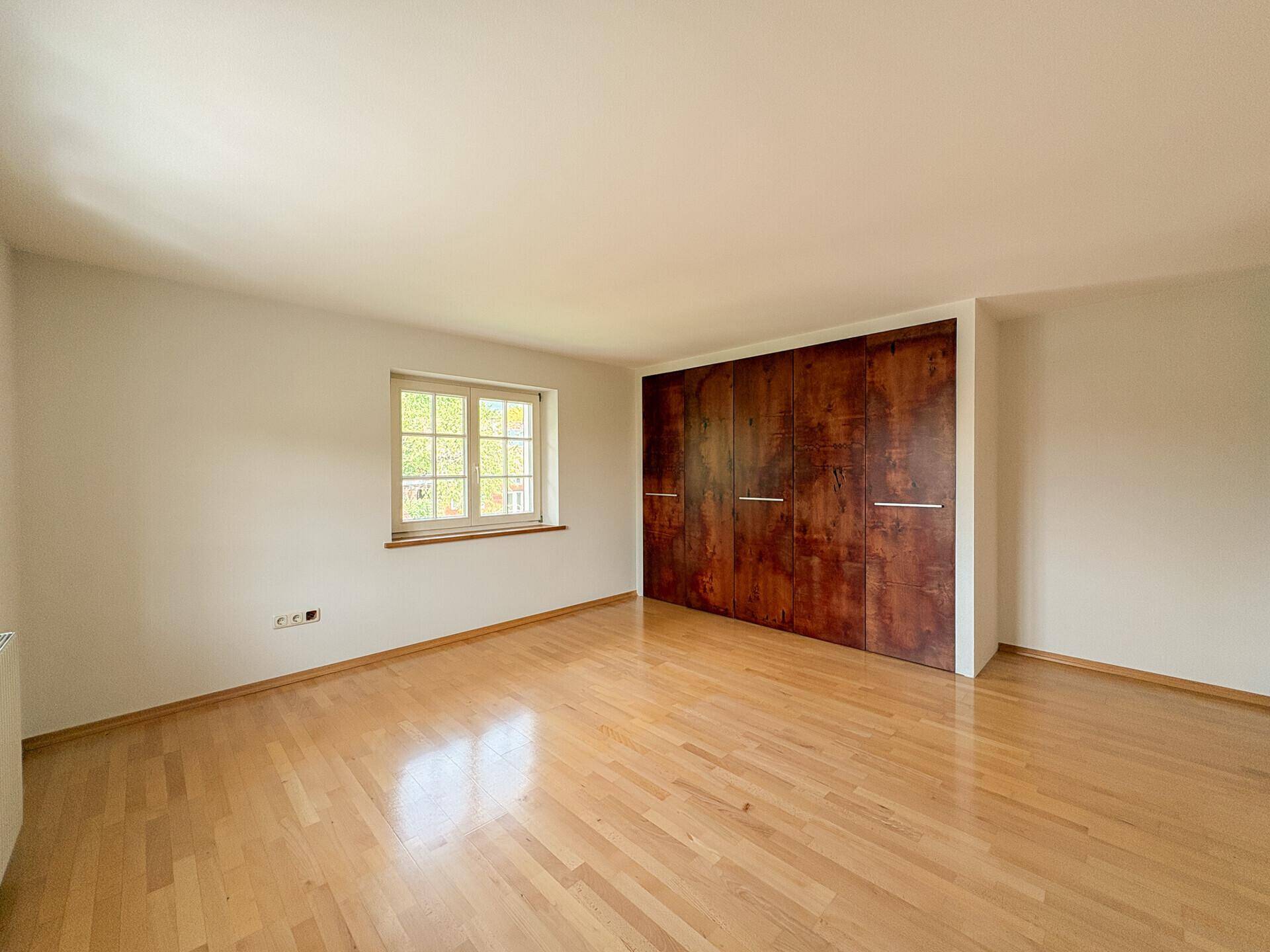 Geräumiges Schlafzimmer mit Holzparkett und großem Einbauschrank.