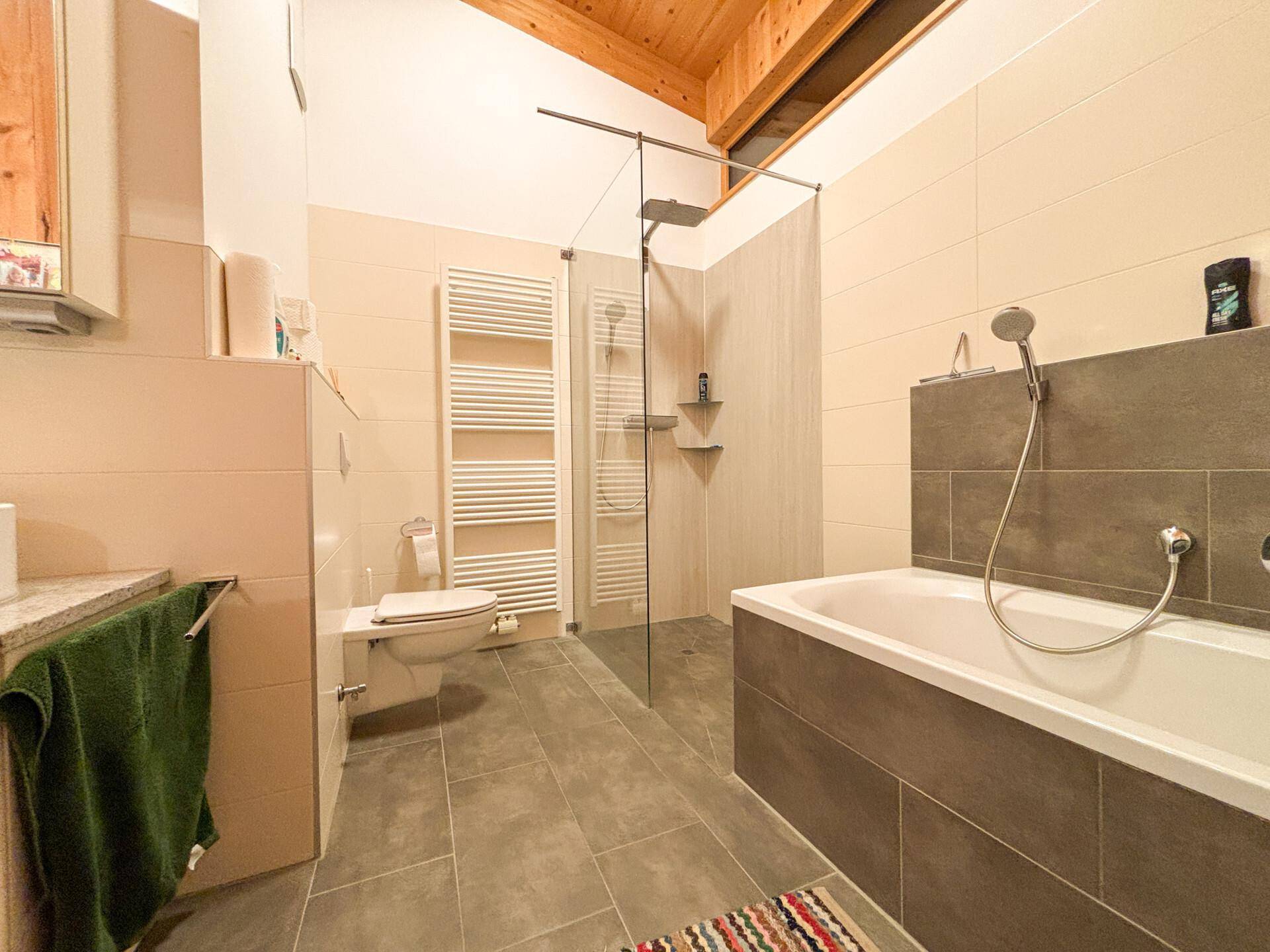 Helles Badezimmer mit begehbarer Dusche, Badewanne und Wand-WC.