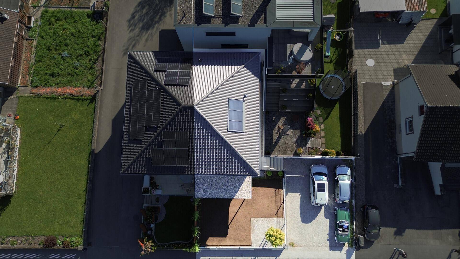 Luftaufnahme des modernen Hauses mit Solaranlage, Garten und Parkplätzen.