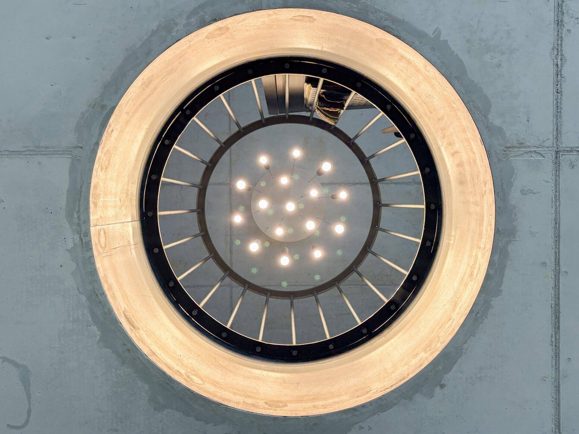 Detailaufnahme einer modernen runden Deckenleuchte in einem Raum mit Betonoptik.