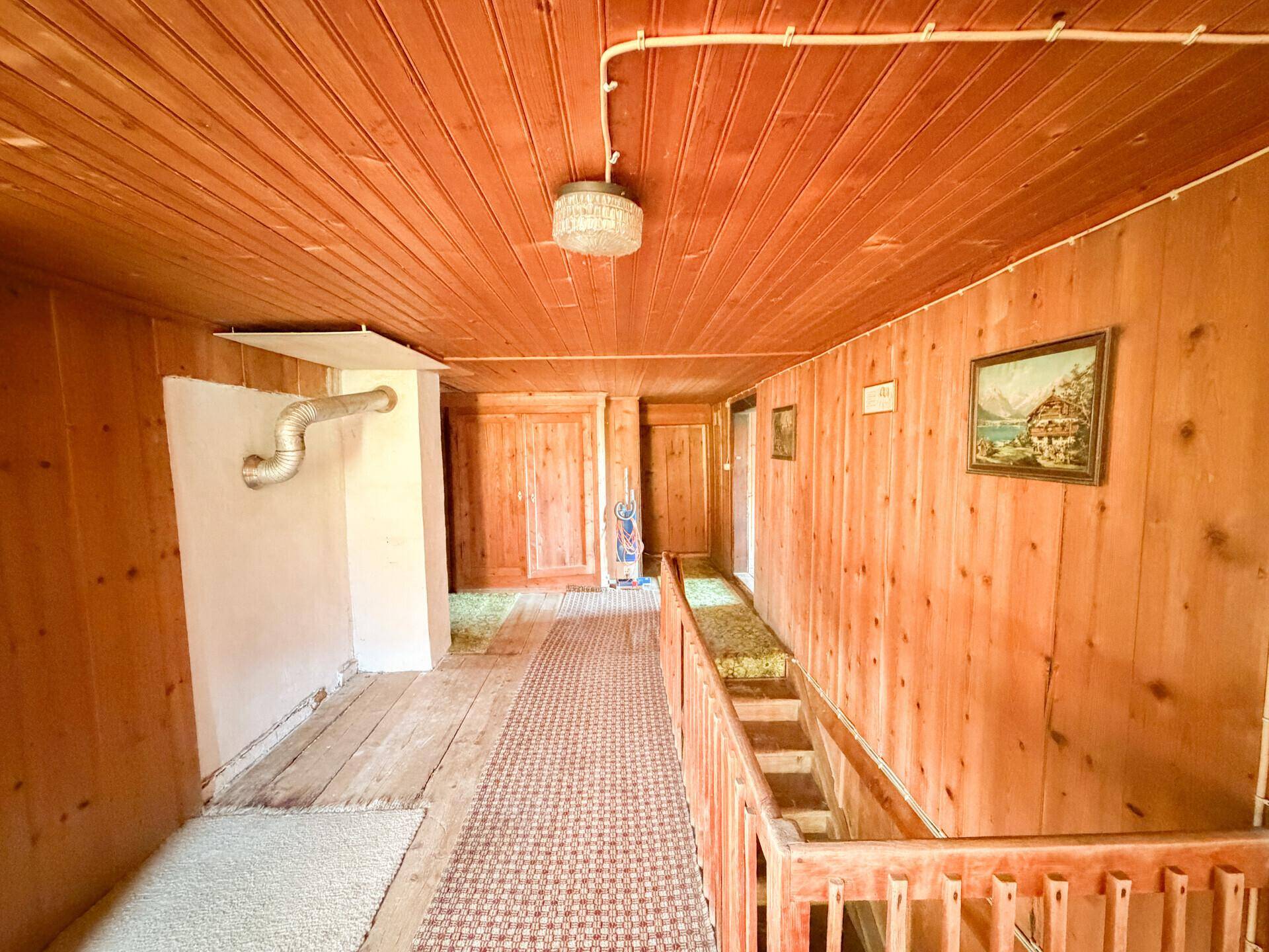 Rustikaler Flur mit Holztäfelung an Wänden und Decke sowie einer Treppe ins Untergeschoss.