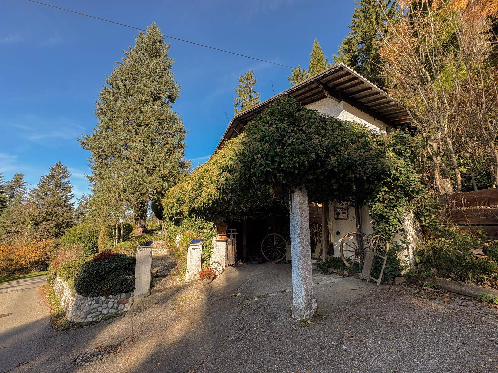 Rustikaler Carport-Bereich mit traditionellen Dekorationen und üppigem Grün.