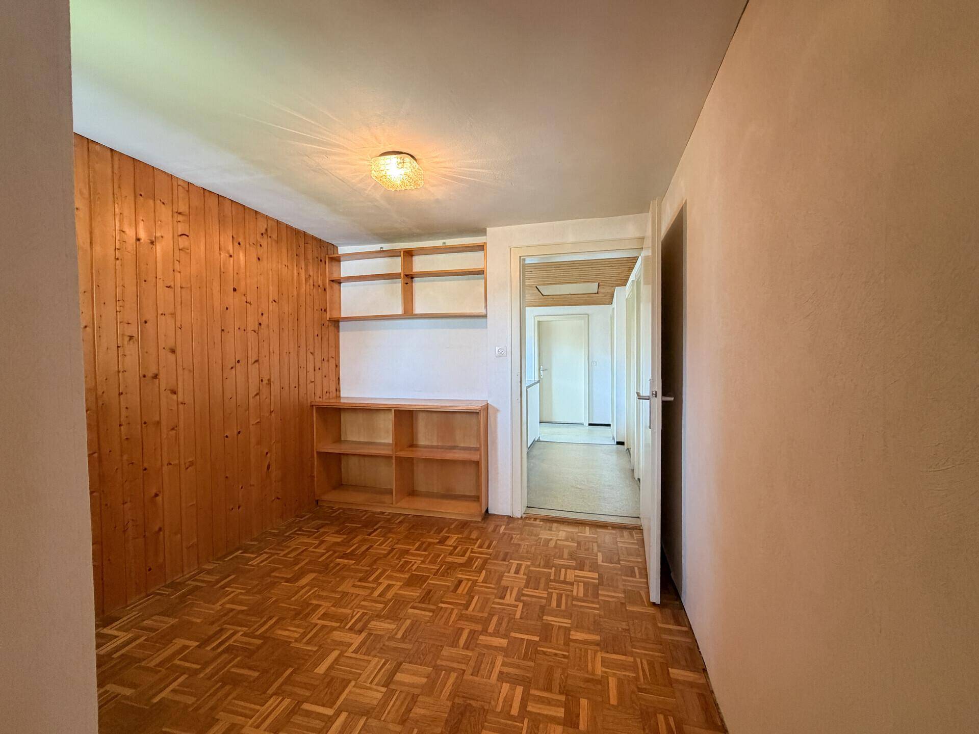 Flur mit Parkettboden, Holzvertäfelung und Regalen, führt zu weiteren Räumen.