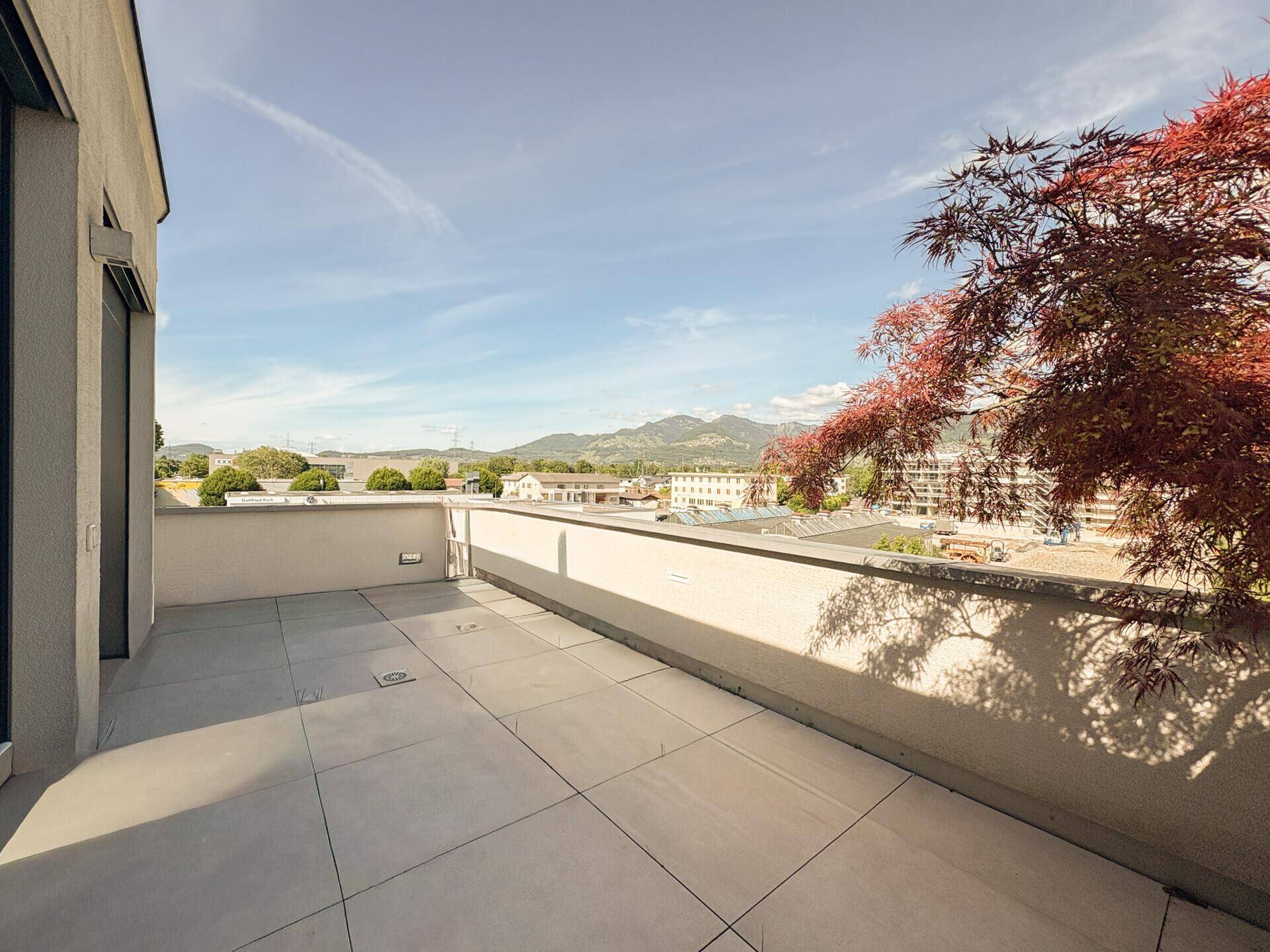 Große, offene Terrasse mit minimalistischer Gestaltung und Panoramablick auf die Umgebung.